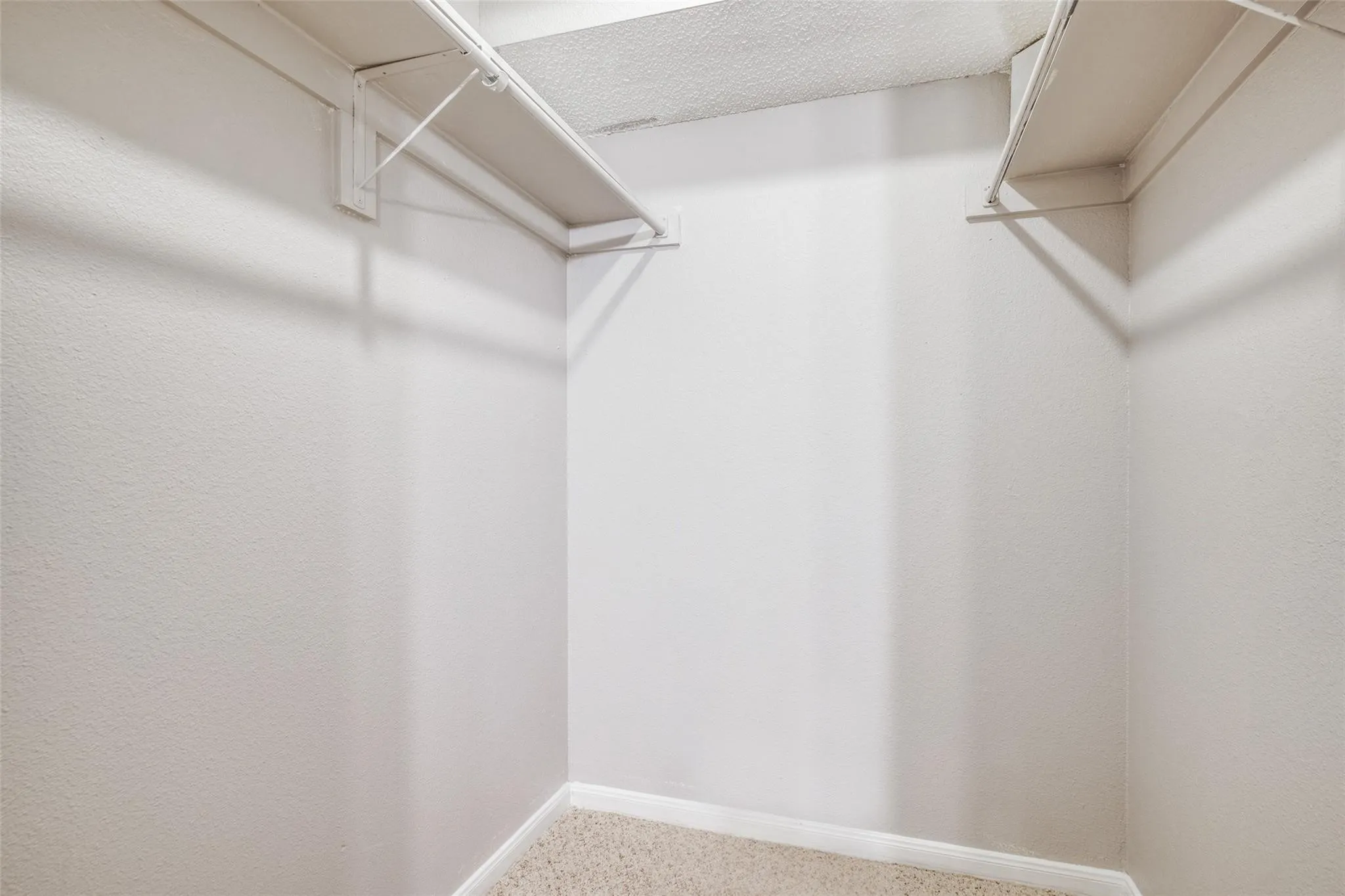 U-shaped closet with wire shelving and a carpeted floor