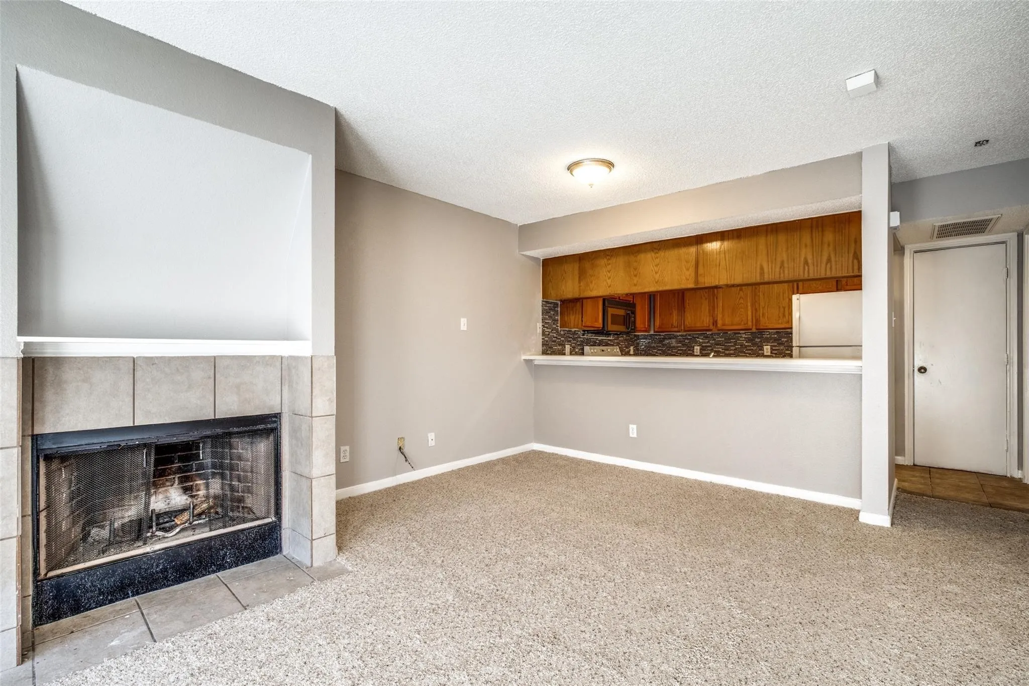 Carpeted living area with a tile-surround fireplace and built-in mantel