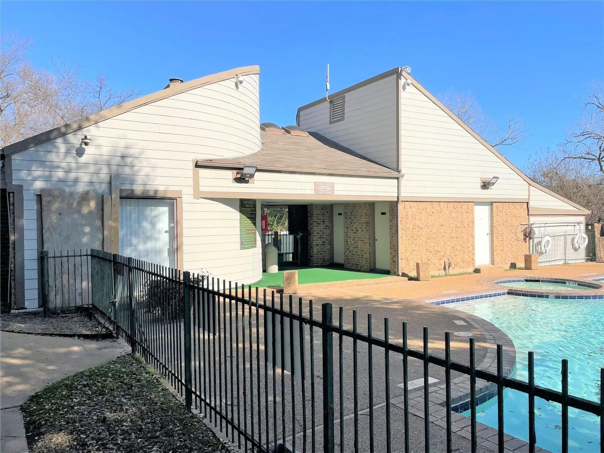 Swimming pool with integrated spa, black metal perimeter fencing, and a surrounding paved deck