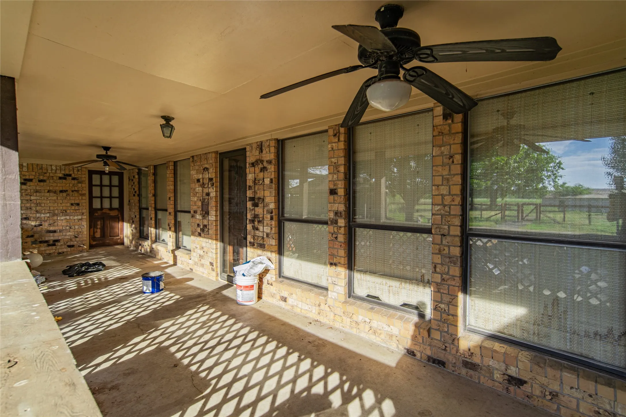 Covered patio with brick wall facade, integrated ceiling fans, and concrete flooring