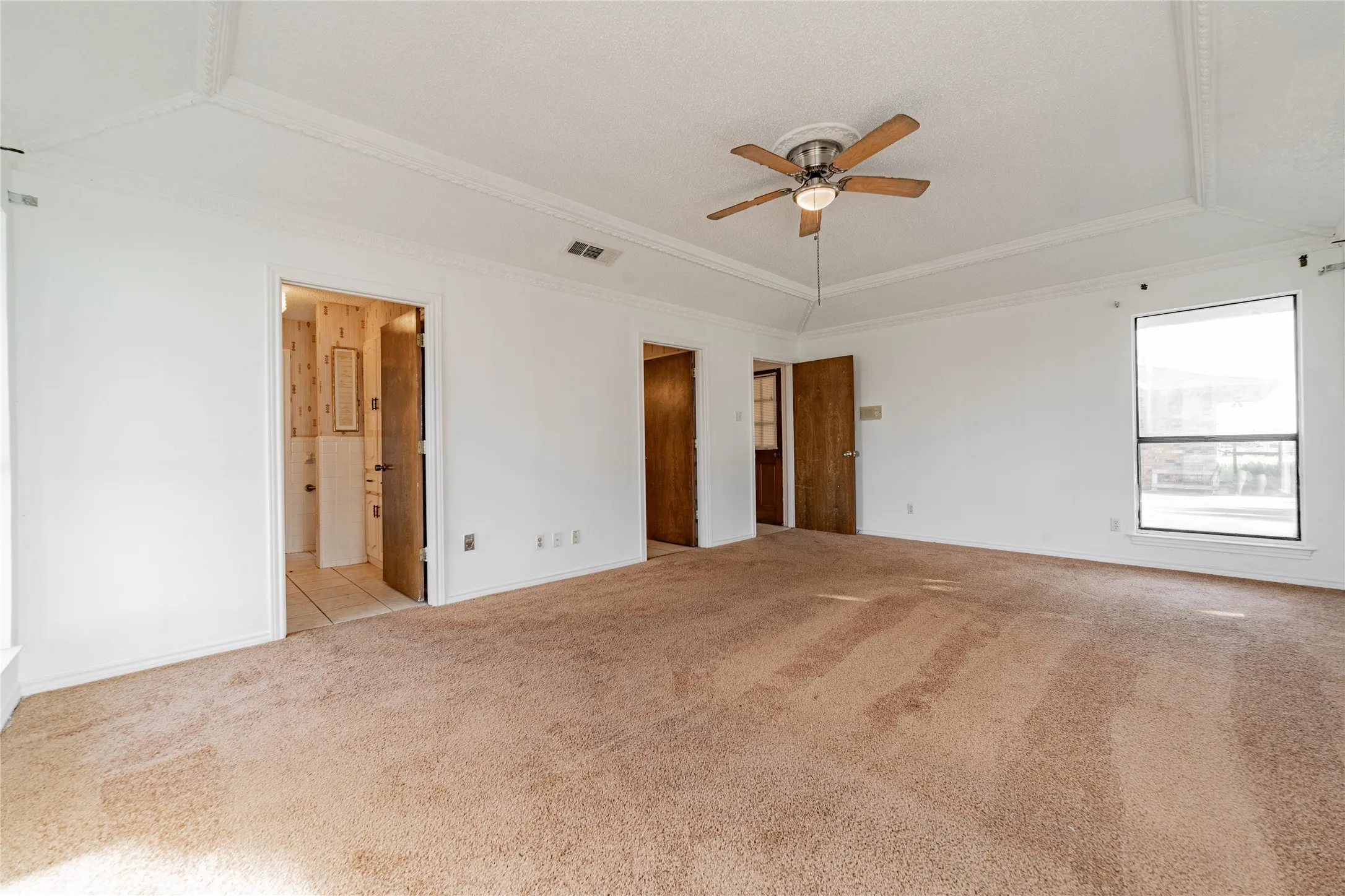 Tray ceiling with crown molding, ceiling fan, and carpeted flooring