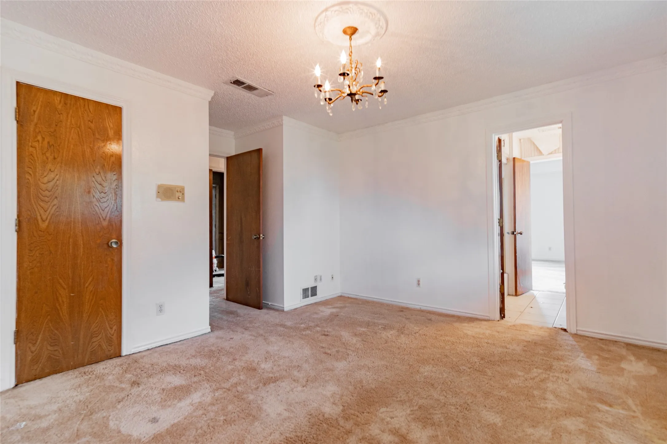 Crown molding, chandelier with ceiling medallion, and wood-panel doors