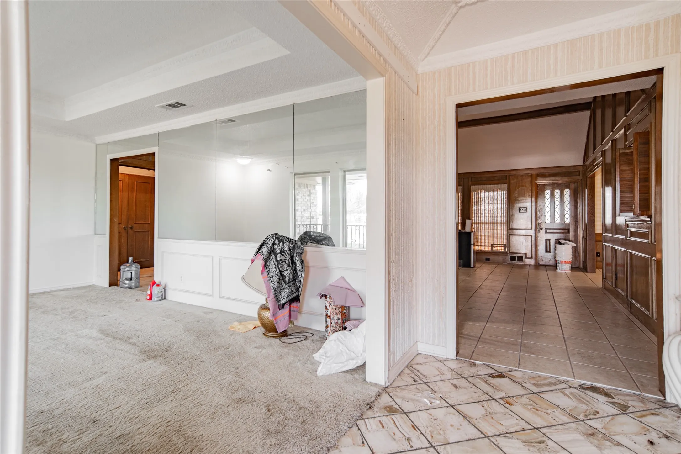 Tray ceiling, wainscoting, full wall mirror, wood paneling, and tile flooring