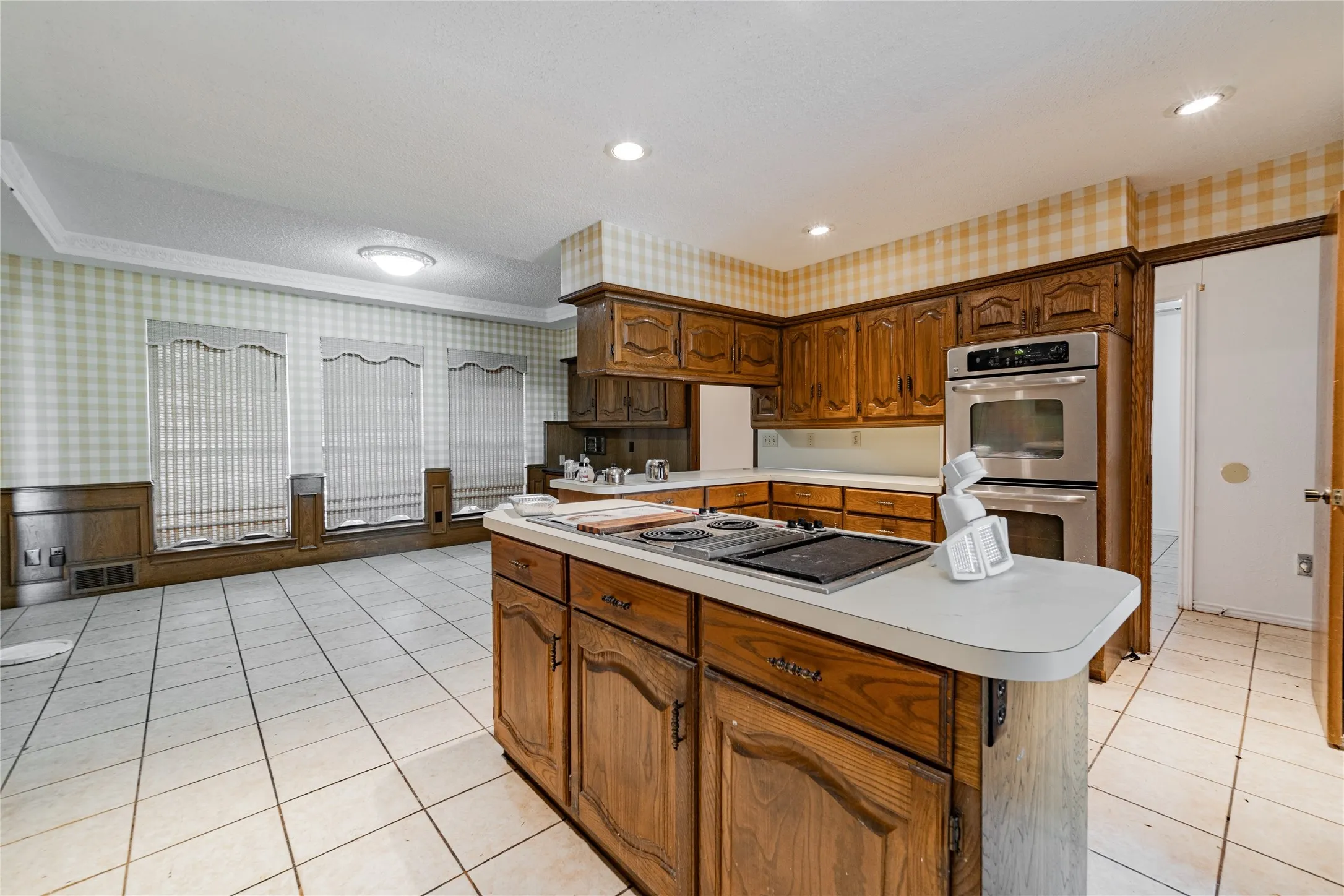 Kitchen featuring wood cabinetry, stainless steel double wall oven, and a center island with an integrated cooktop