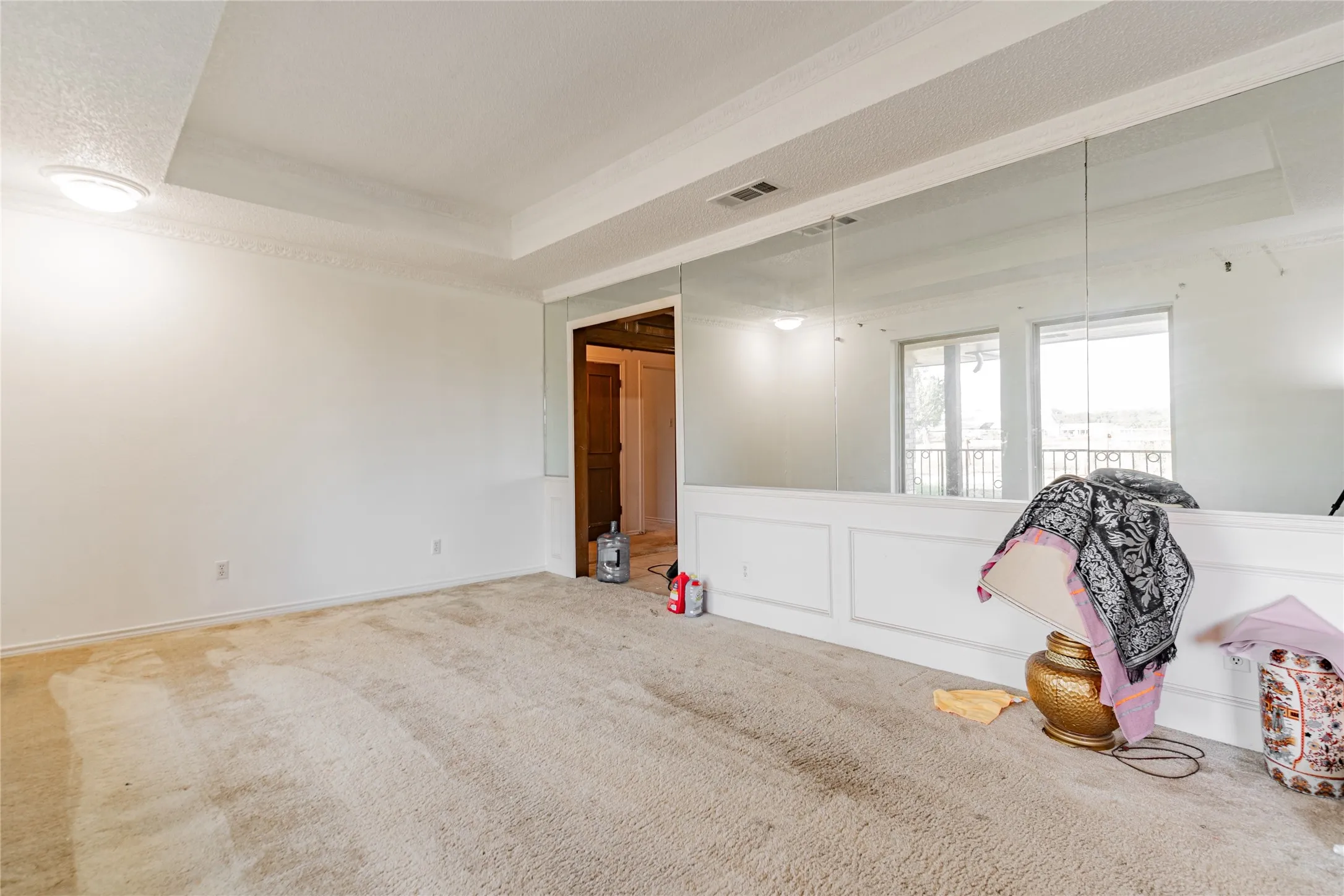 Recessed ceiling with crown molding, wall-mounted mirror panels, and white wainscoting