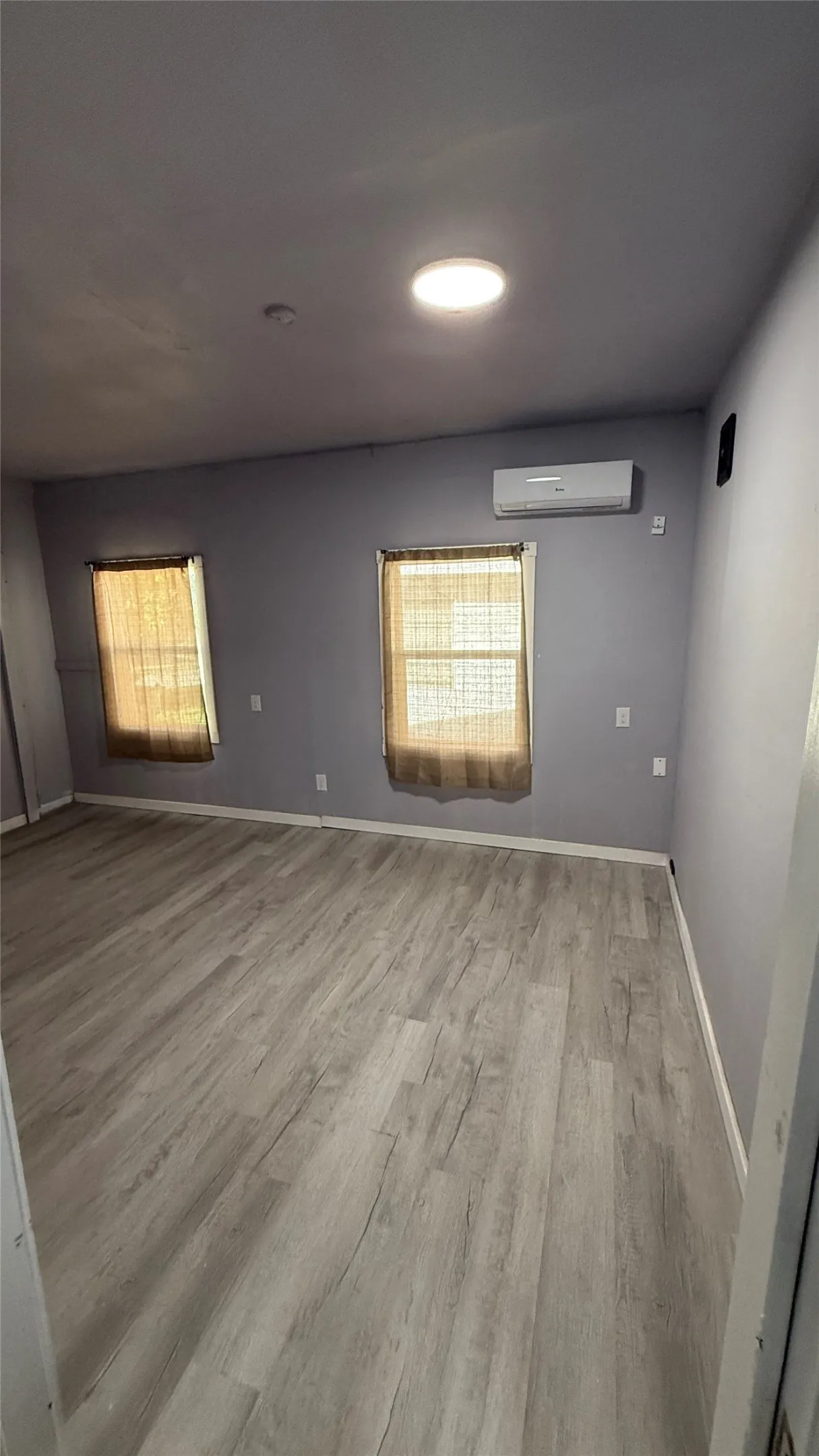 Wood-finish flooring, recessed ceiling lighting, and a wall-mounted climate control unit