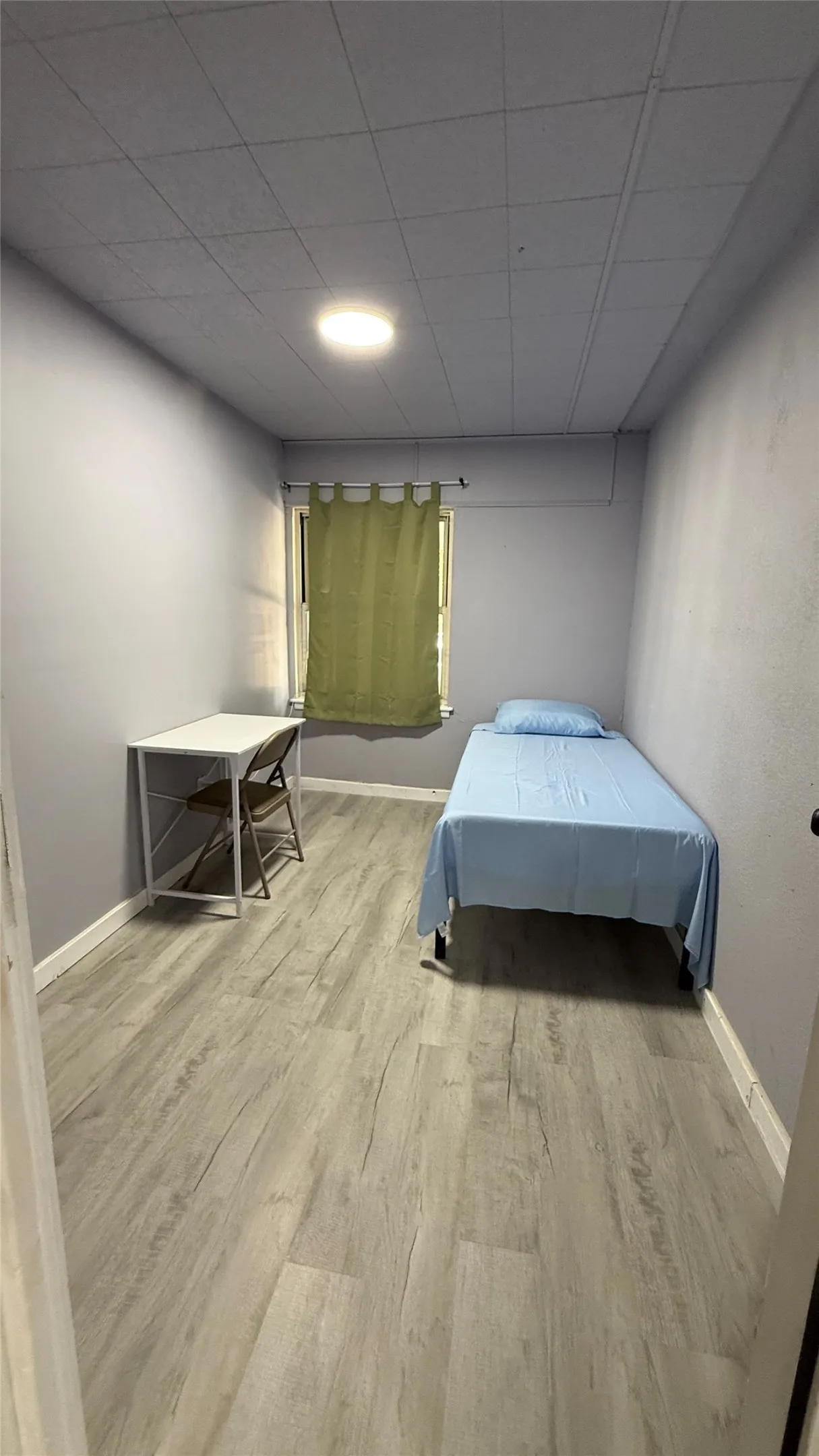 Recessed ceiling lighting, durable wood-finish flooring, and window with privacy curtain
