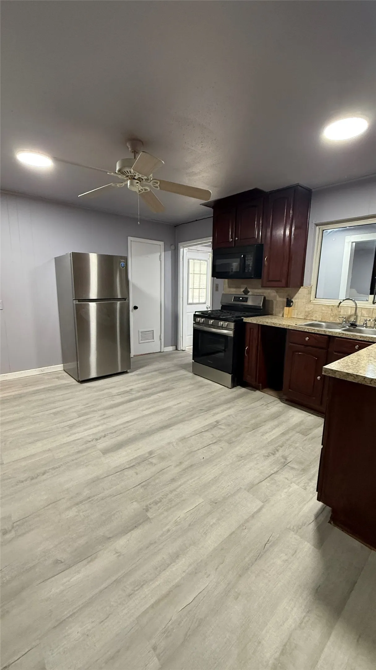 Kitchen with wood-finish flooring, dark wood cabinetry, and stainless steel appliances