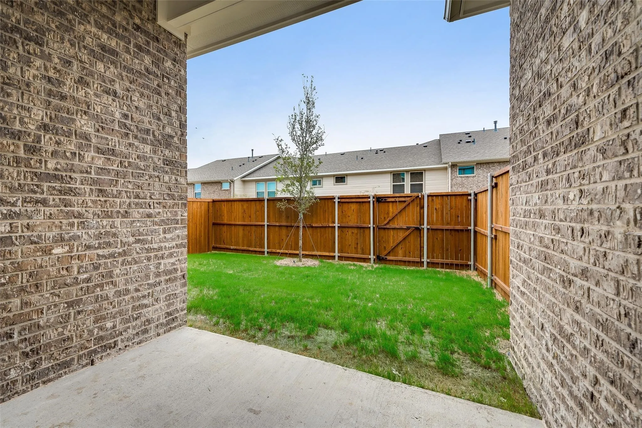 Private yard with a wood fence, concrete patio, and mature landscaping