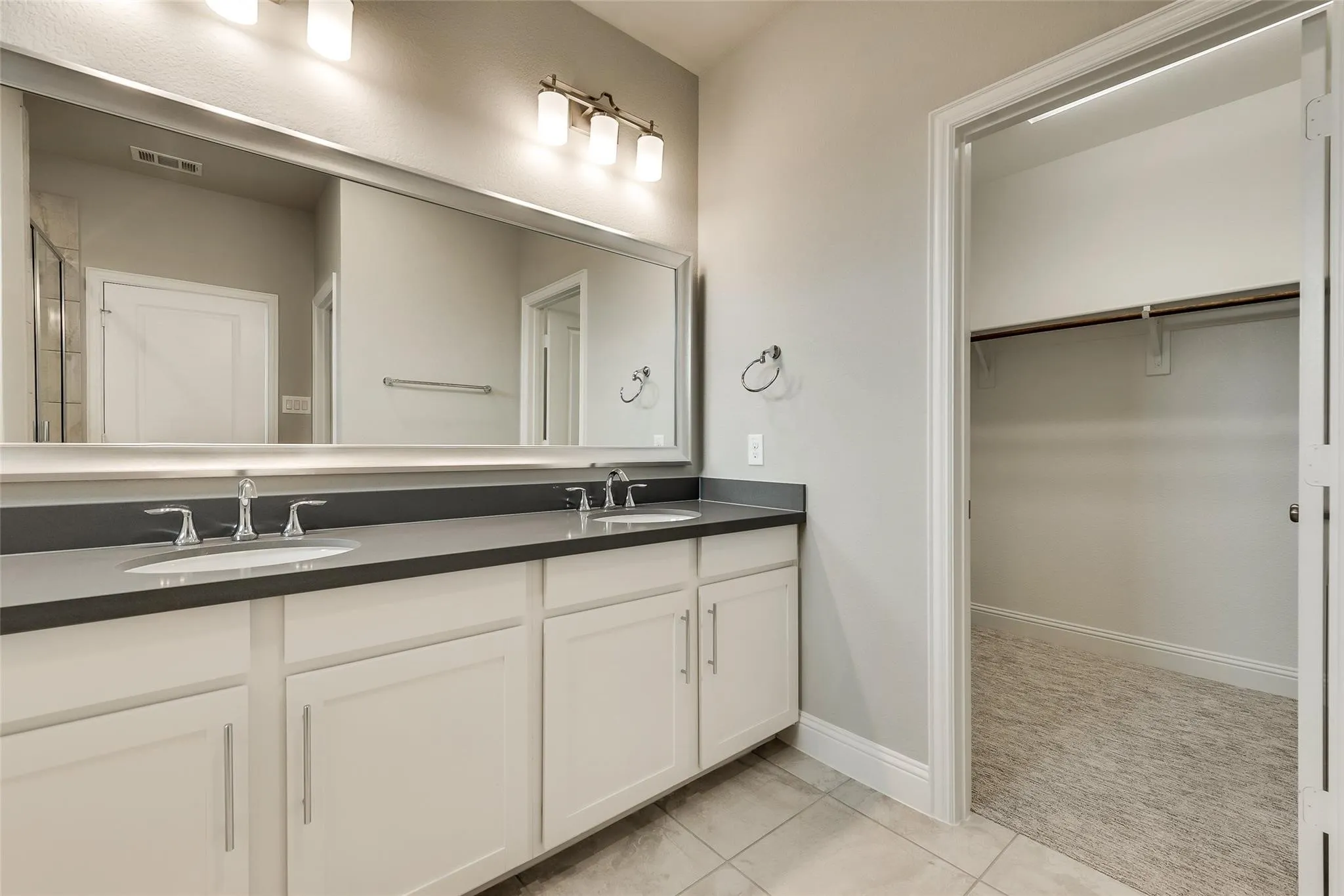 Dual vanity with undermount sinks, sleek dark countertops, and a full-width mirror