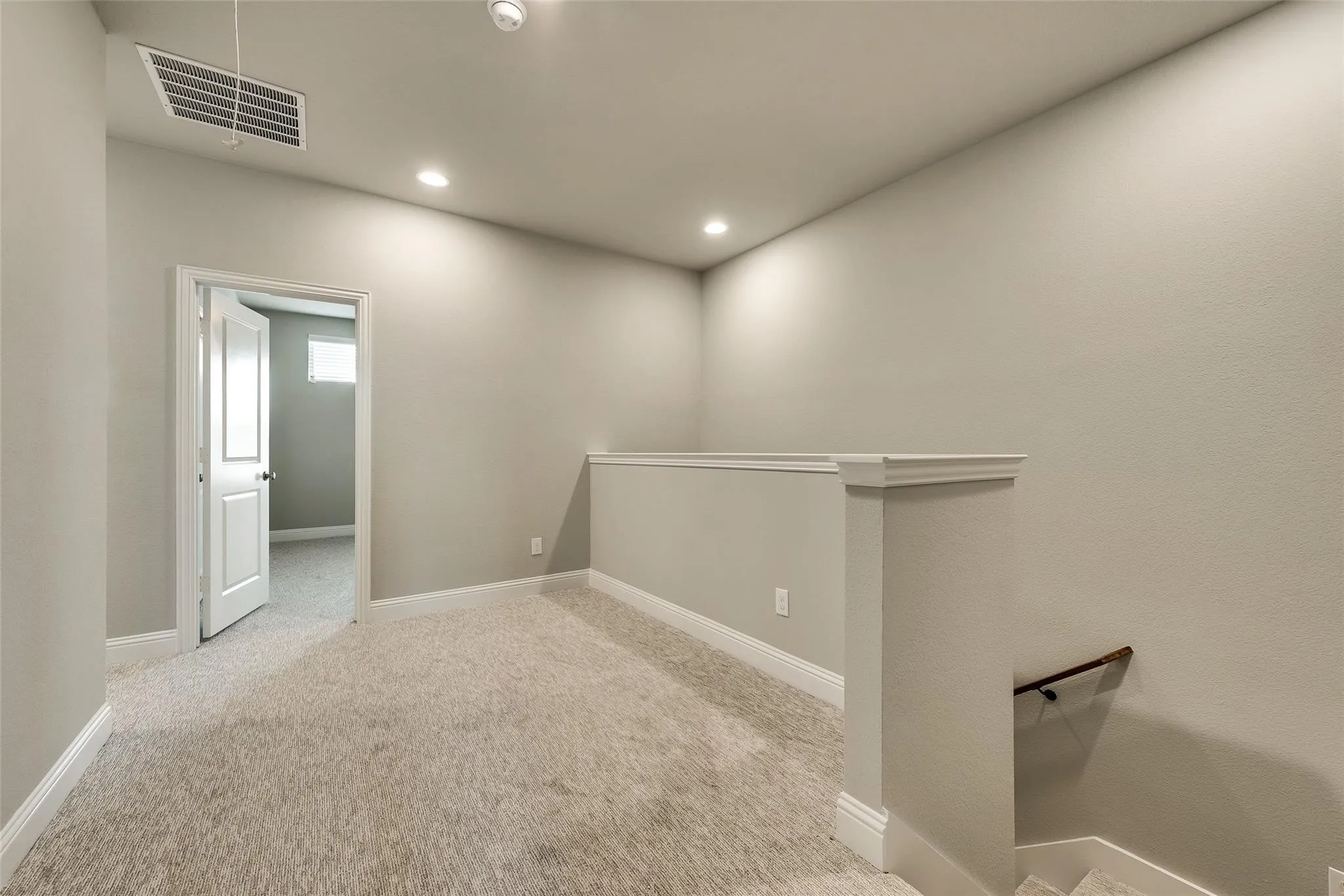 Loft area featuring neutral carpeting, recessed lighting, and a white balustrade