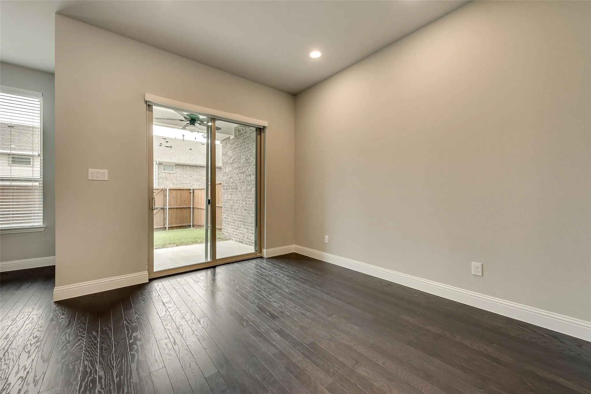 Dark wood-finish flooring, sliding glass door, recessed lighting, and a white trim package