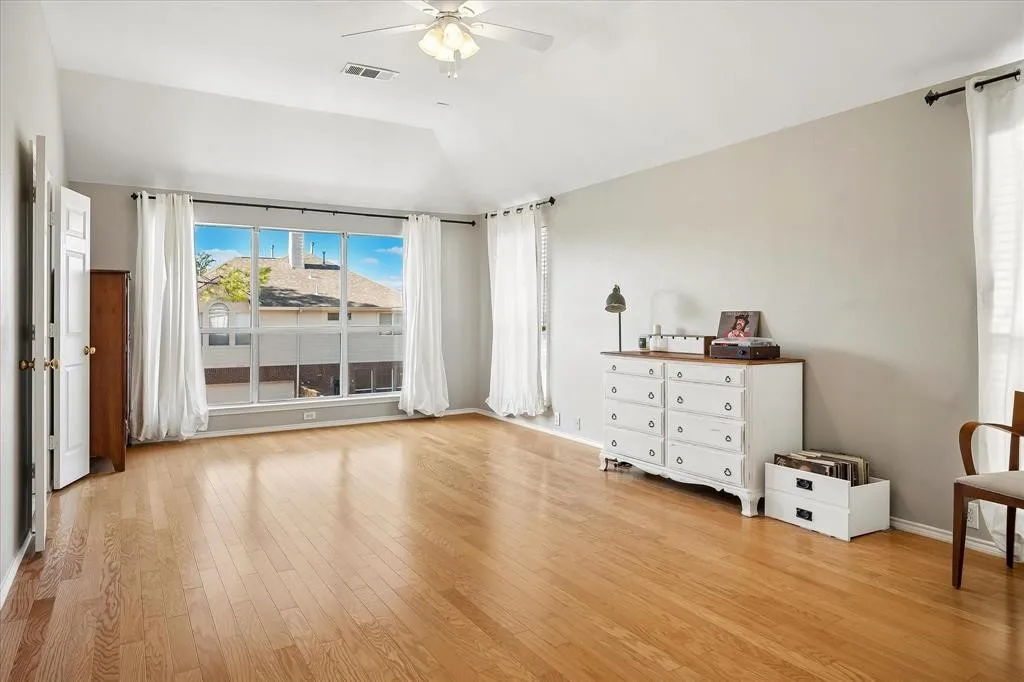 Hardwood flooring, vaulted ceiling, large multi-pane window, ceiling fan, and painted interior walls