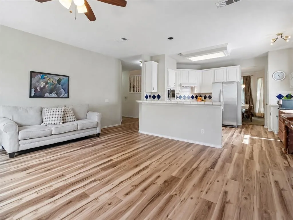 Open-concept living area with wood-finish flooring, a ceiling fan, and recessed lighting