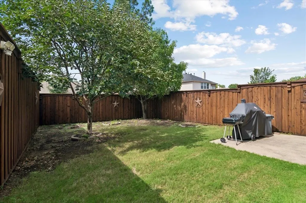 Backyard featuring a wood privacy fence, concrete patio, and established trees