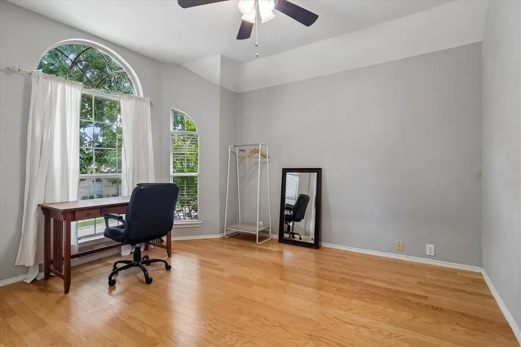 Vaulted ceiling with a ceiling fan, arched windows, and wood-finish flooring