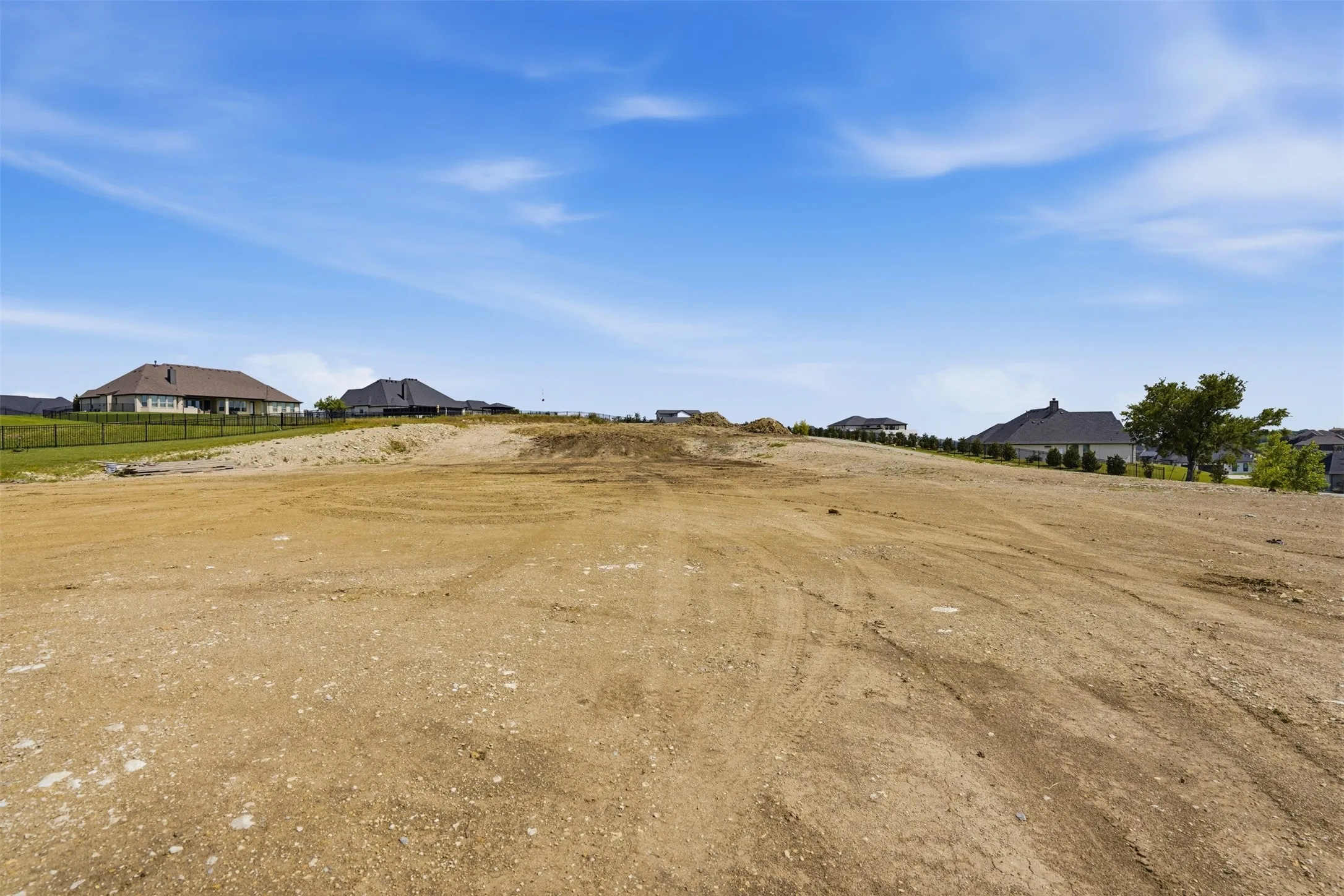 Expansive land parcel with graded terrain, surrounded by a developing residential area