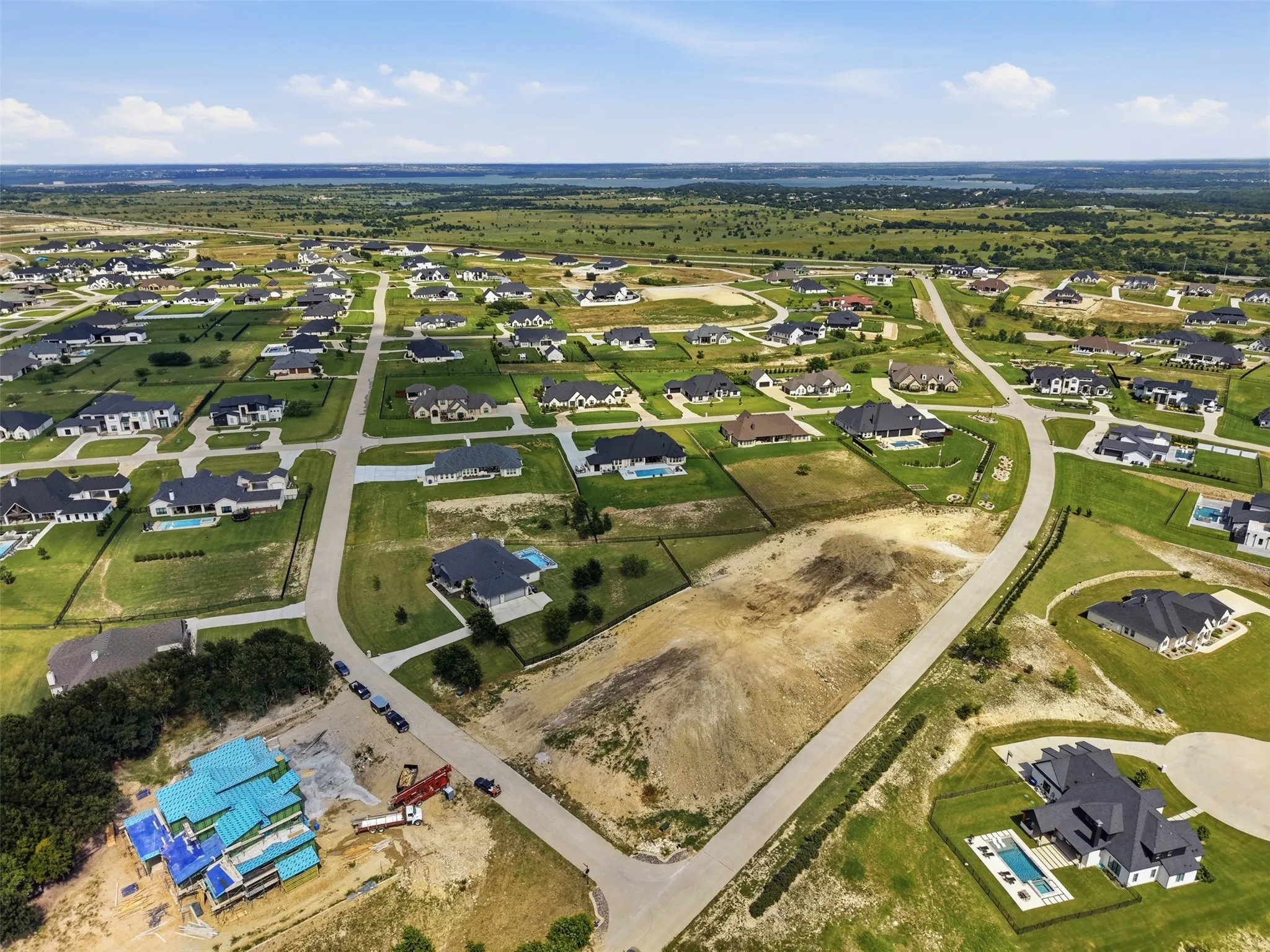 Expansive residential development with paved roadways, abundant green space, and a distant natural landscape