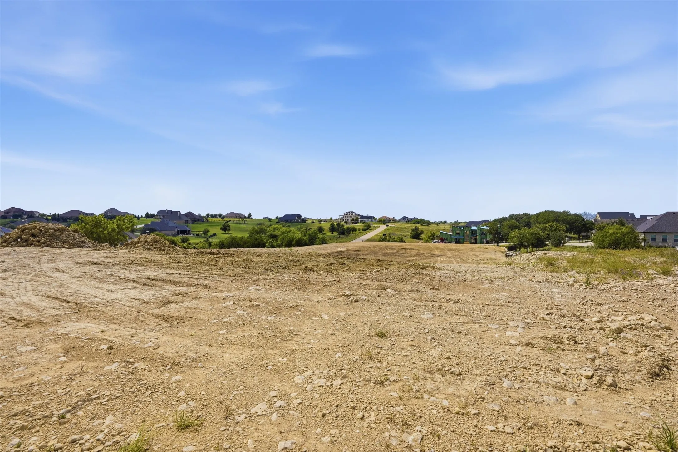 Expansive land parcel featuring cleared terrain and distant neighborhood structures