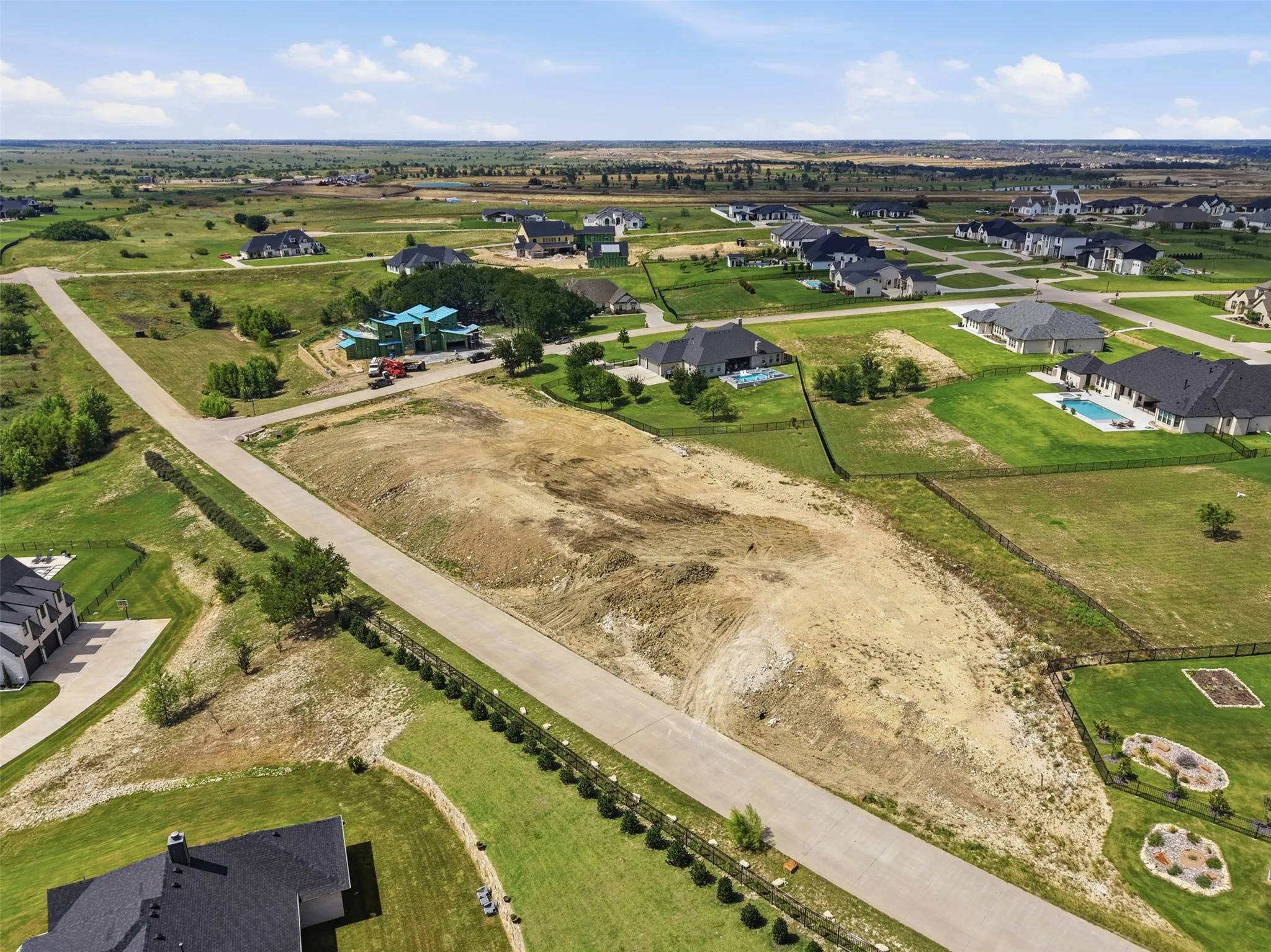 Expansive lot featuring graded terrain, paved road frontage, and surrounding residential properties