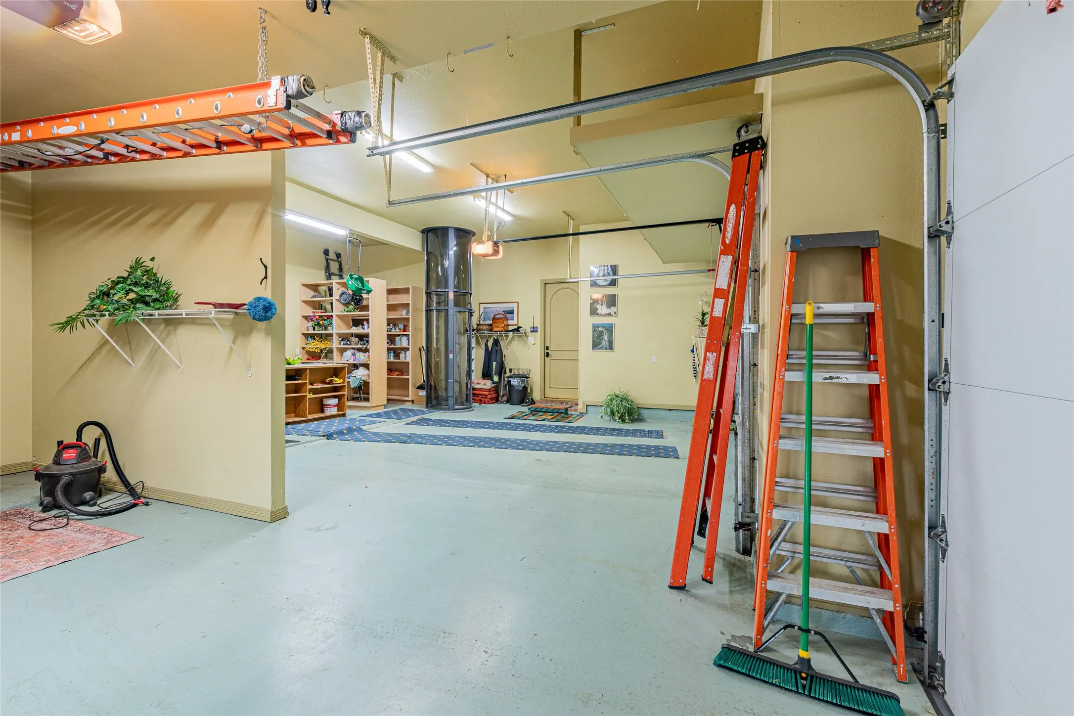 Spacious garage area featuring light-colored flooring, abundant ceiling lighting, and overhead garage door tracks