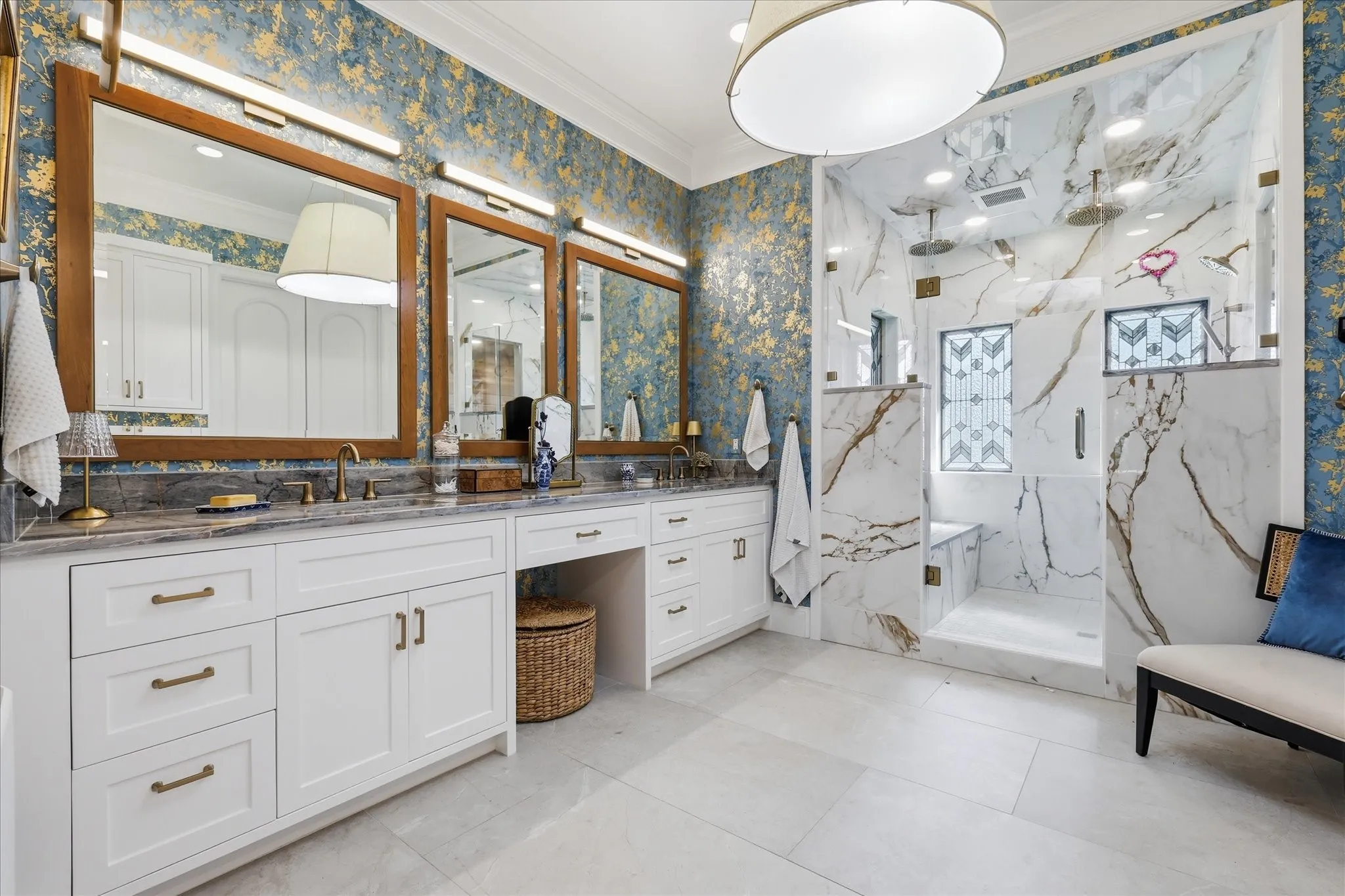 Double vanity with white cabinetry and gold-toned hardware, quartz countertop, and three framed mirrors