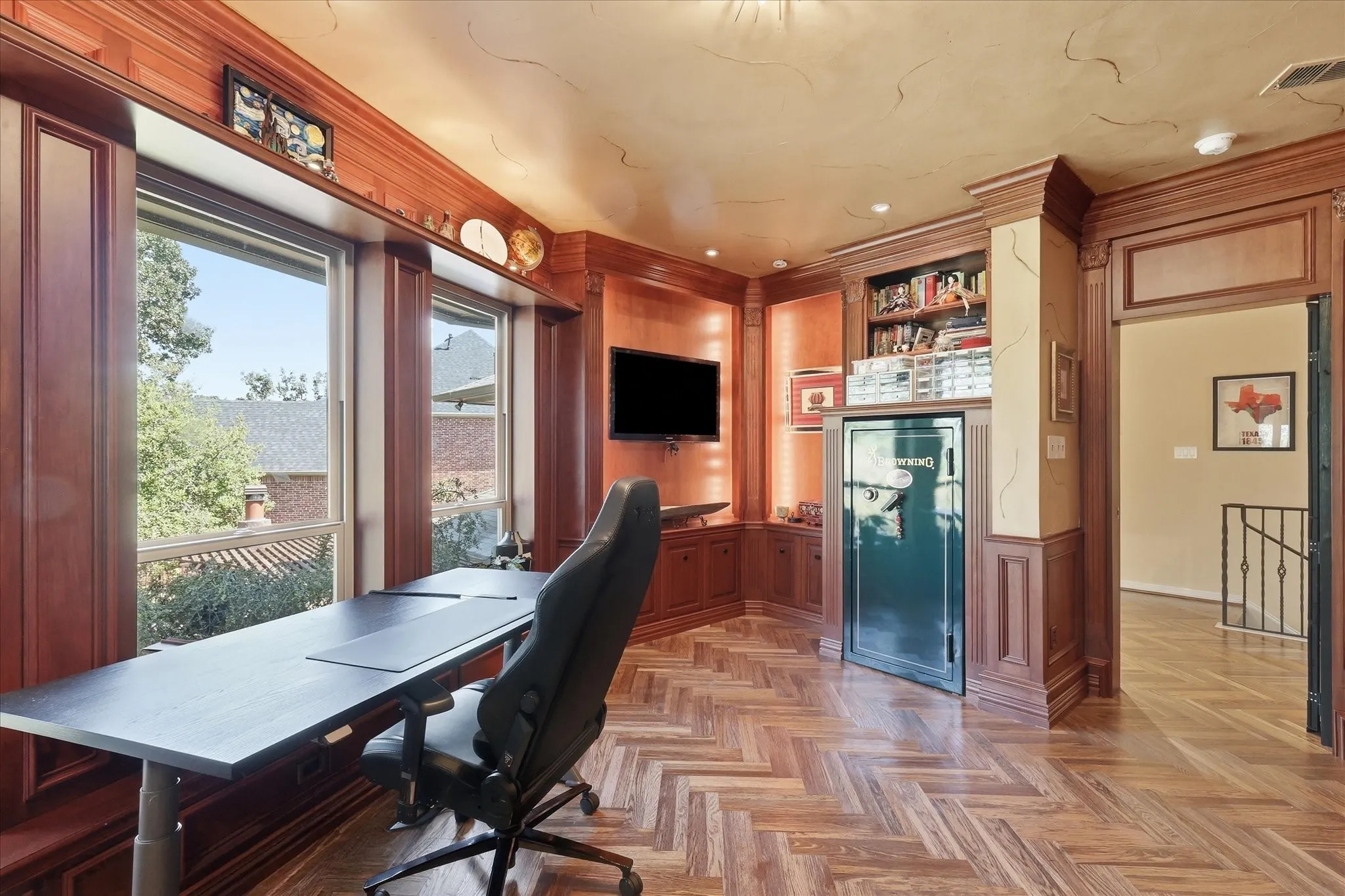 Herringbone wood-finish flooring, custom built-in cabinetry, substantial wood trim and molding, large windows, and a built-in safe