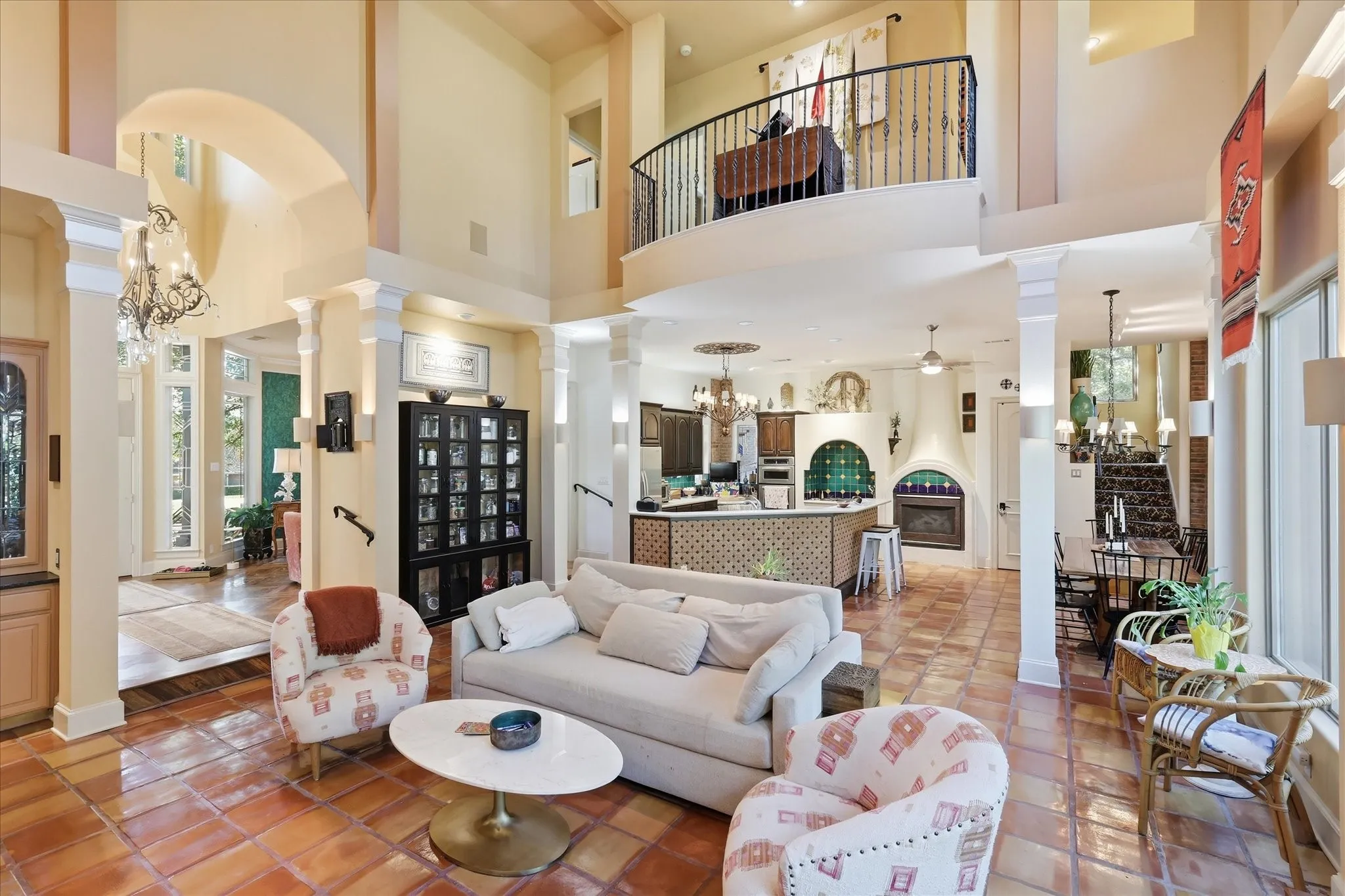 Two-story ceiling, arched doorways, tiled flooring, built-in display cabinetry, and an upper-level balcony
