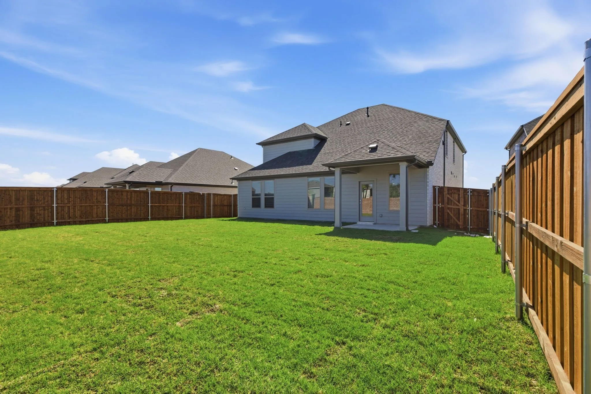 Expansive yard with wood fencing, a covered patio, and a grass lawn