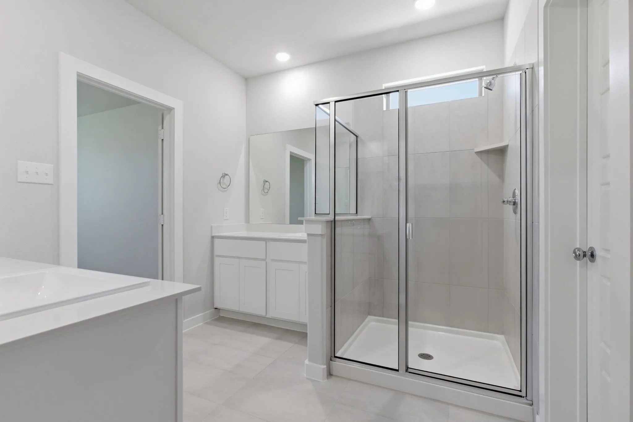 Spacious bathroom featuring a built-in bathtub, a walk-in shower with clear glass enclosure, and a vanity with a white countertop