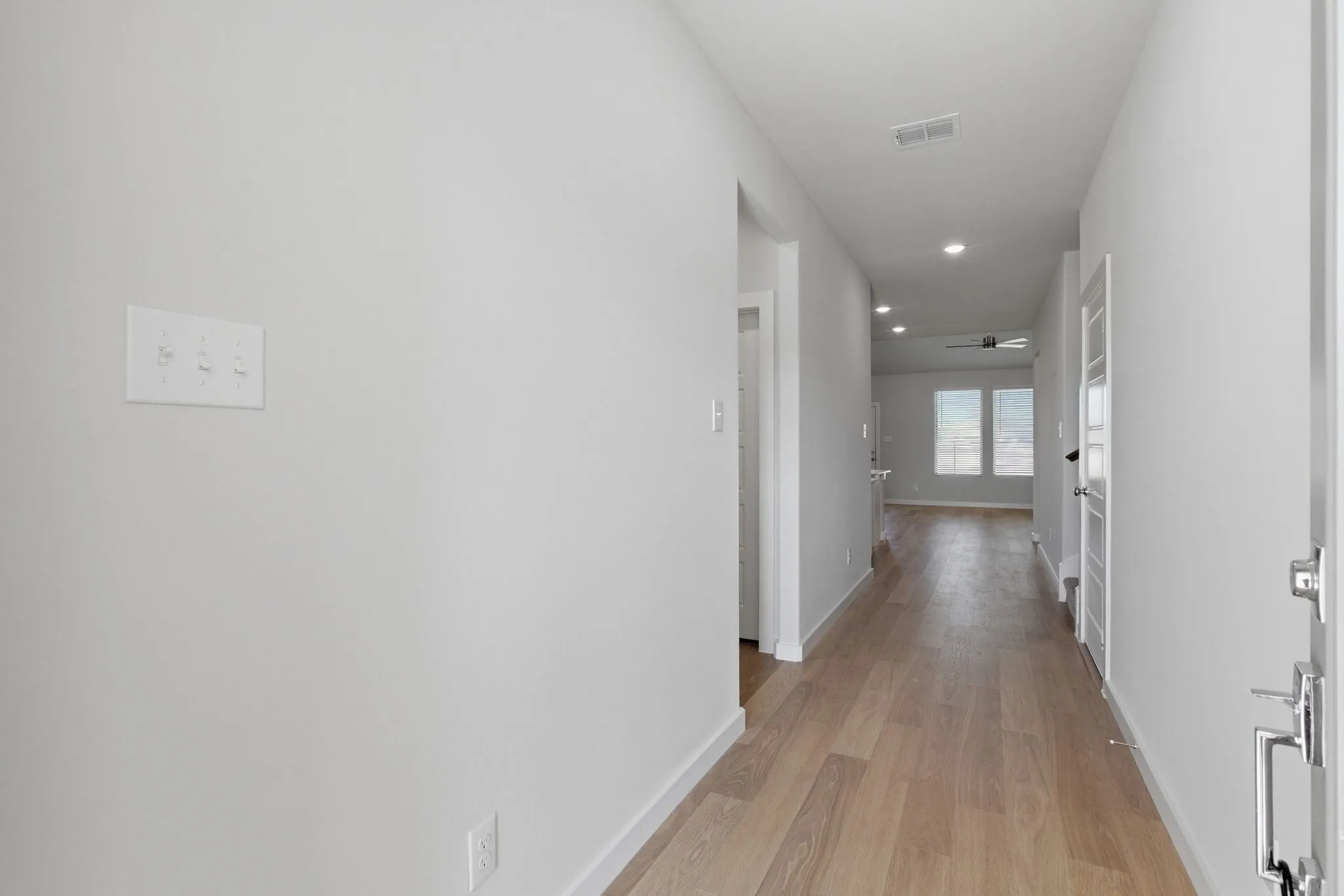 Recessed lighting illuminates wood-finish flooring throughout the hallway