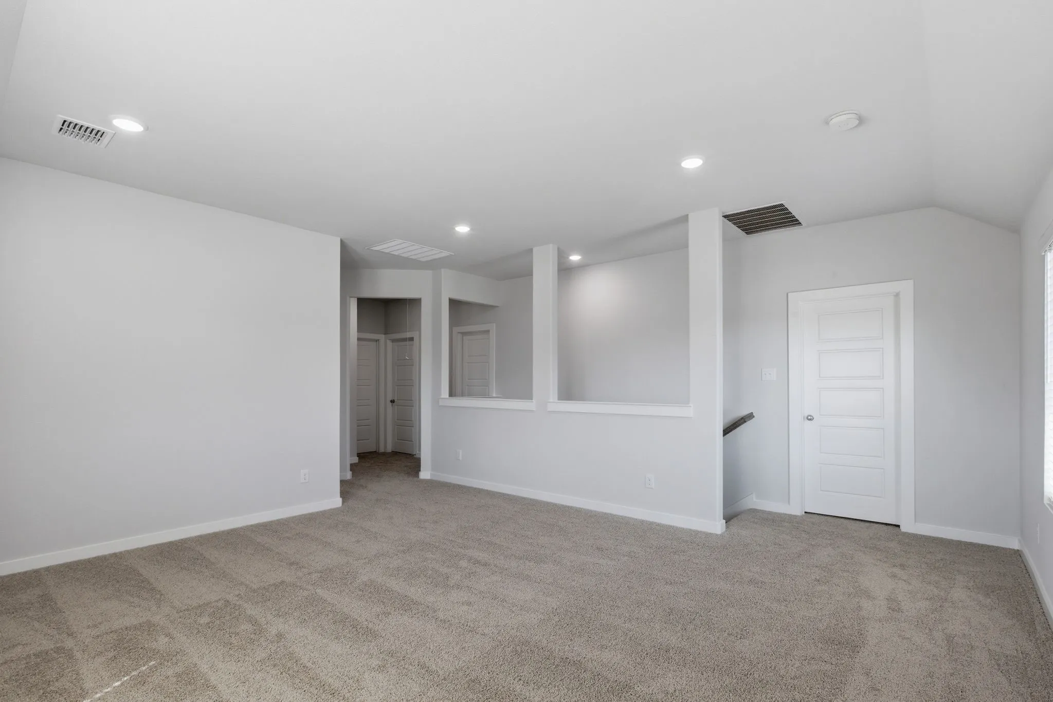 Recessed lighting, light gray wall finishes, light carpeting, white trim, and a paneled white door