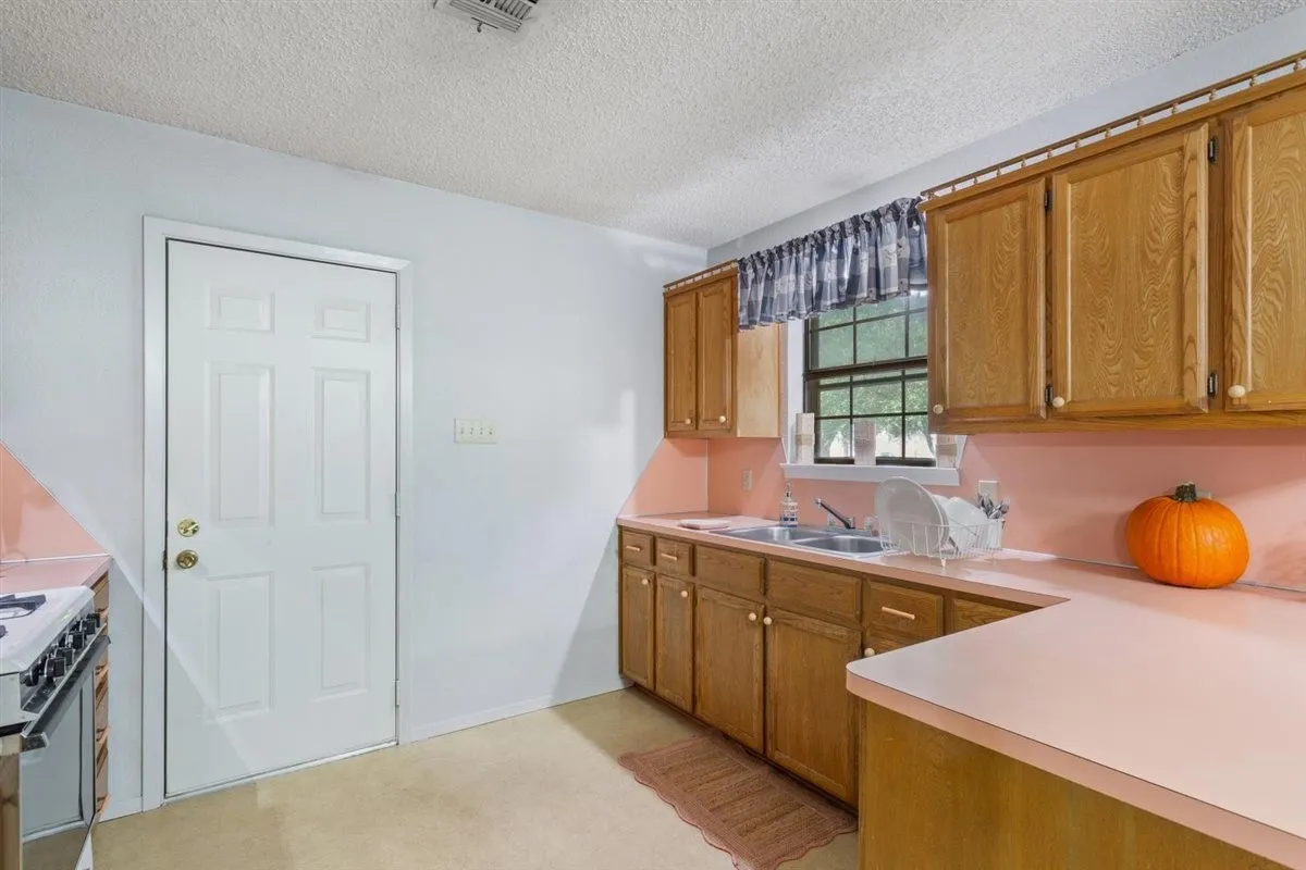 Kitchen featuring wood-finish cabinetry, a double basin sink, and a built-in oven with a stovetop
