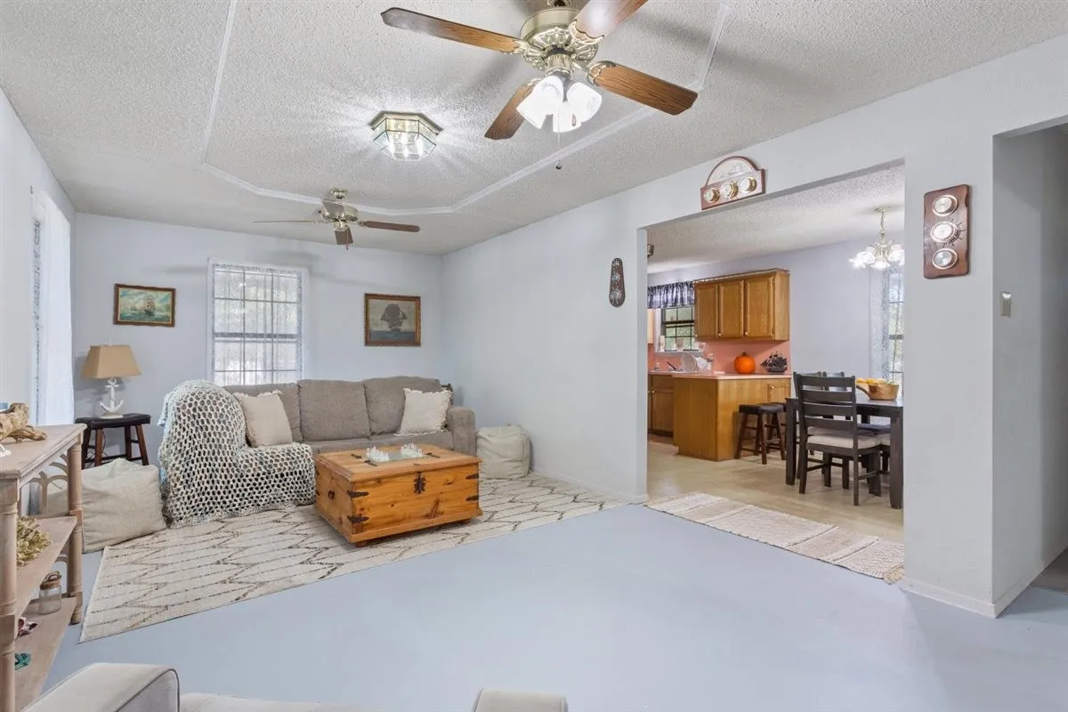 Tray ceiling with decorative trim, multiple ceiling fans, recessed lighting fixture, arched entryway, and wood-finish cabinetry