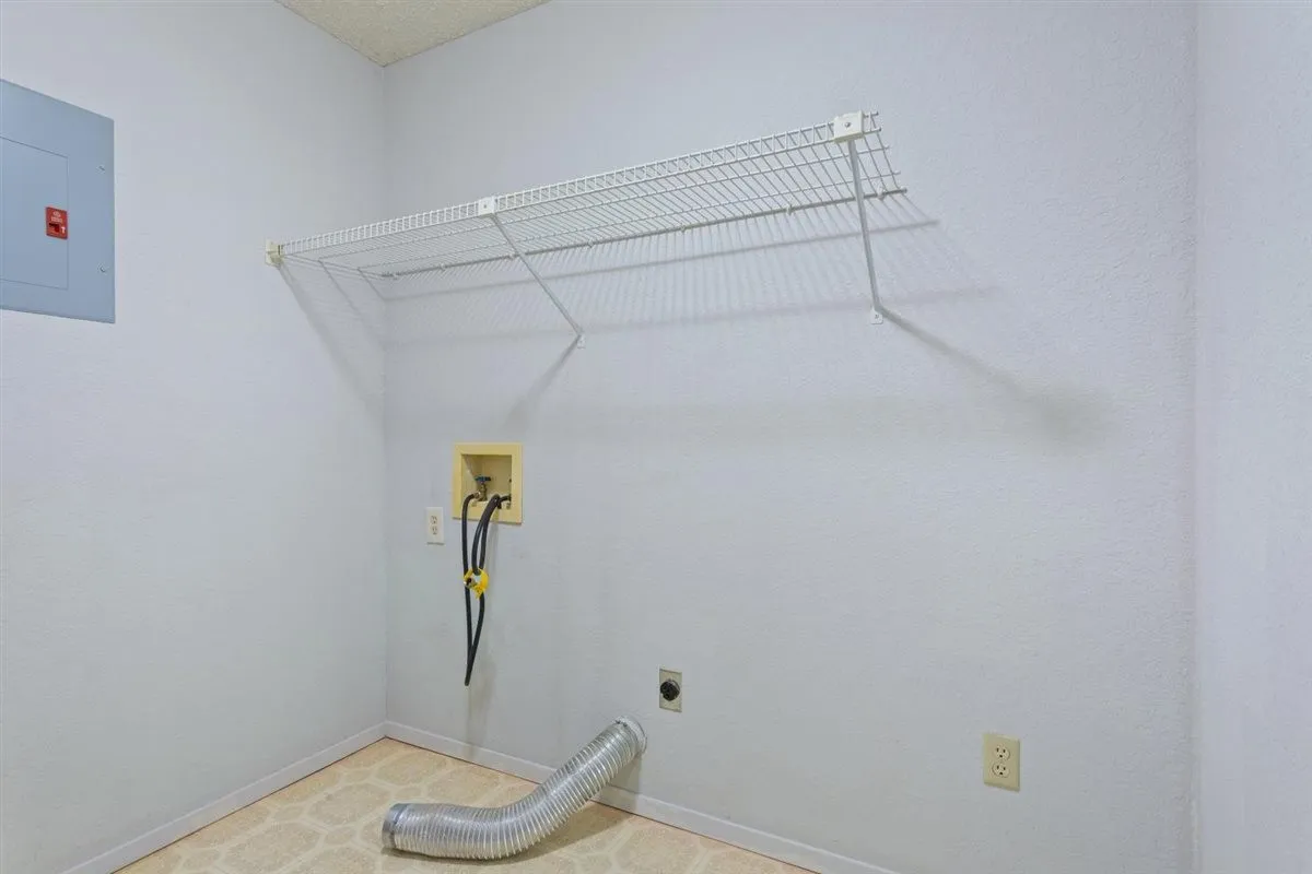 Laundry area featuring a wire storage shelf, utility hookups, and a light-colored patterned floor