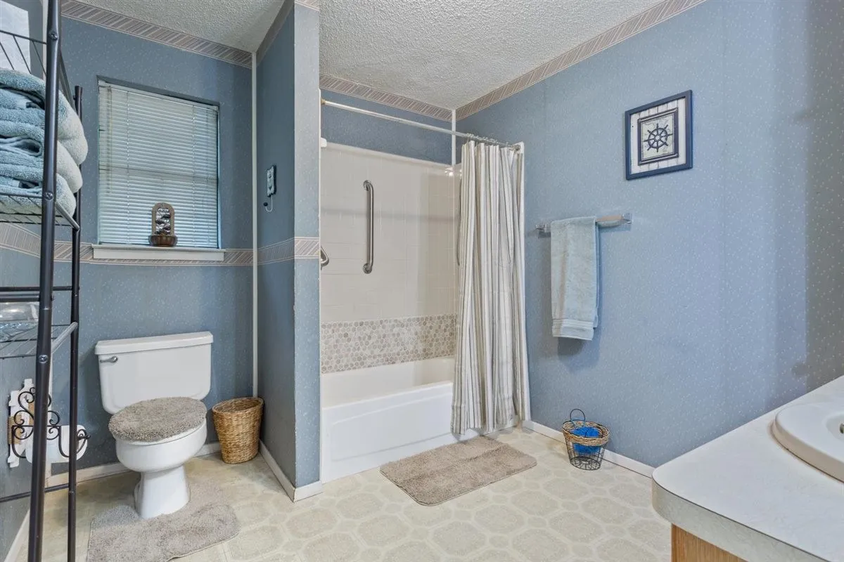 Bathtub and shower combination with mosaic tile surround and grab bars