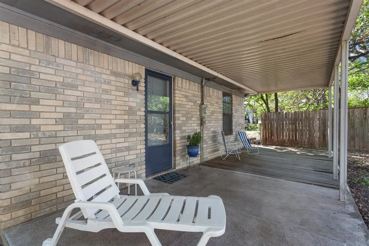 Covered patio with a corrugated metal roof, brick exterior, and wood deck