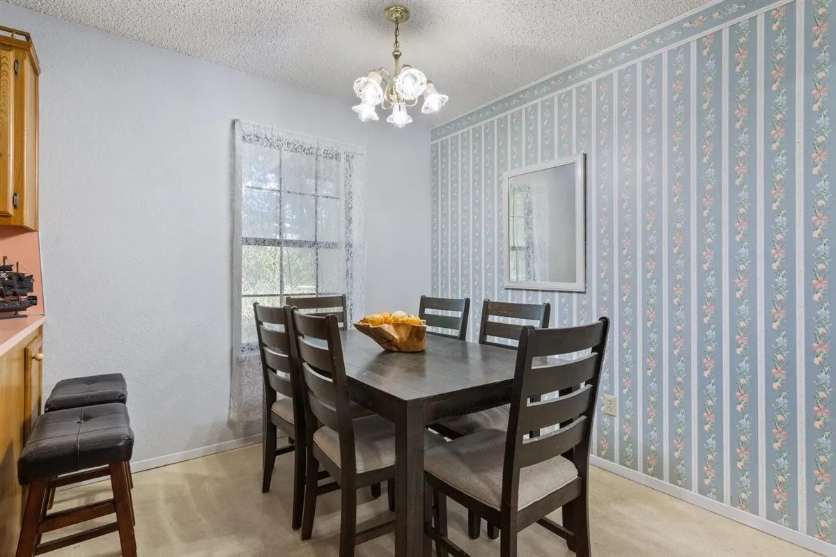 Dining area with a window, decorative wallpaper, and a ceiling-mounted light fixture