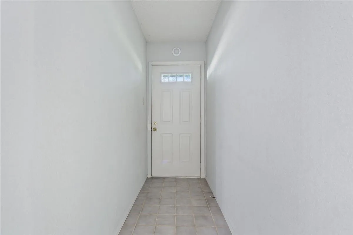 Entryway featuring a white paneled door with decorative glass inserts, recessed ceiling lighting, and neutral tone tile flooring