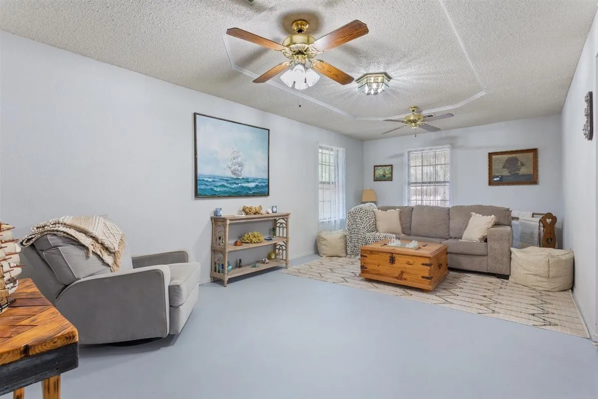 Recessed ceiling detail, multiple ceiling fans, light-toned walls, and abundant natural light