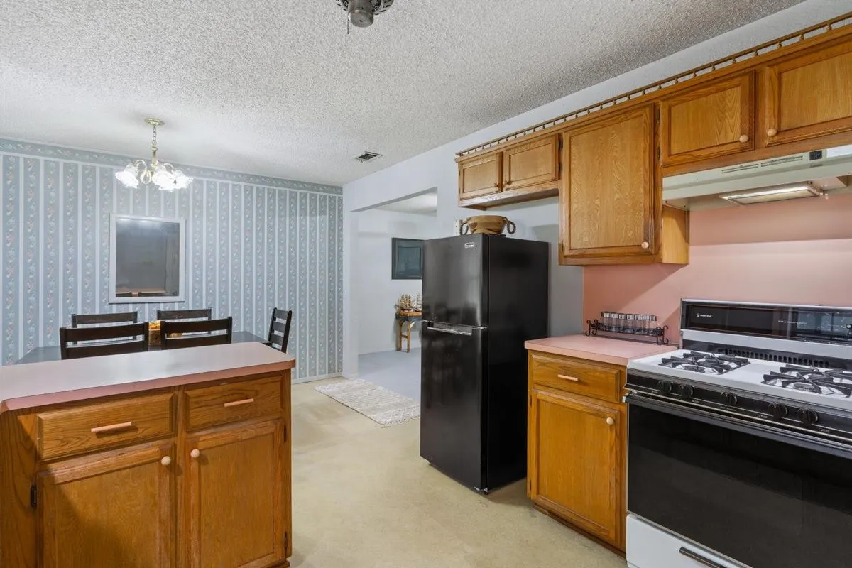 Kitchen with wood-finish cabinetry, a gas range, and a full-size black refrigerator