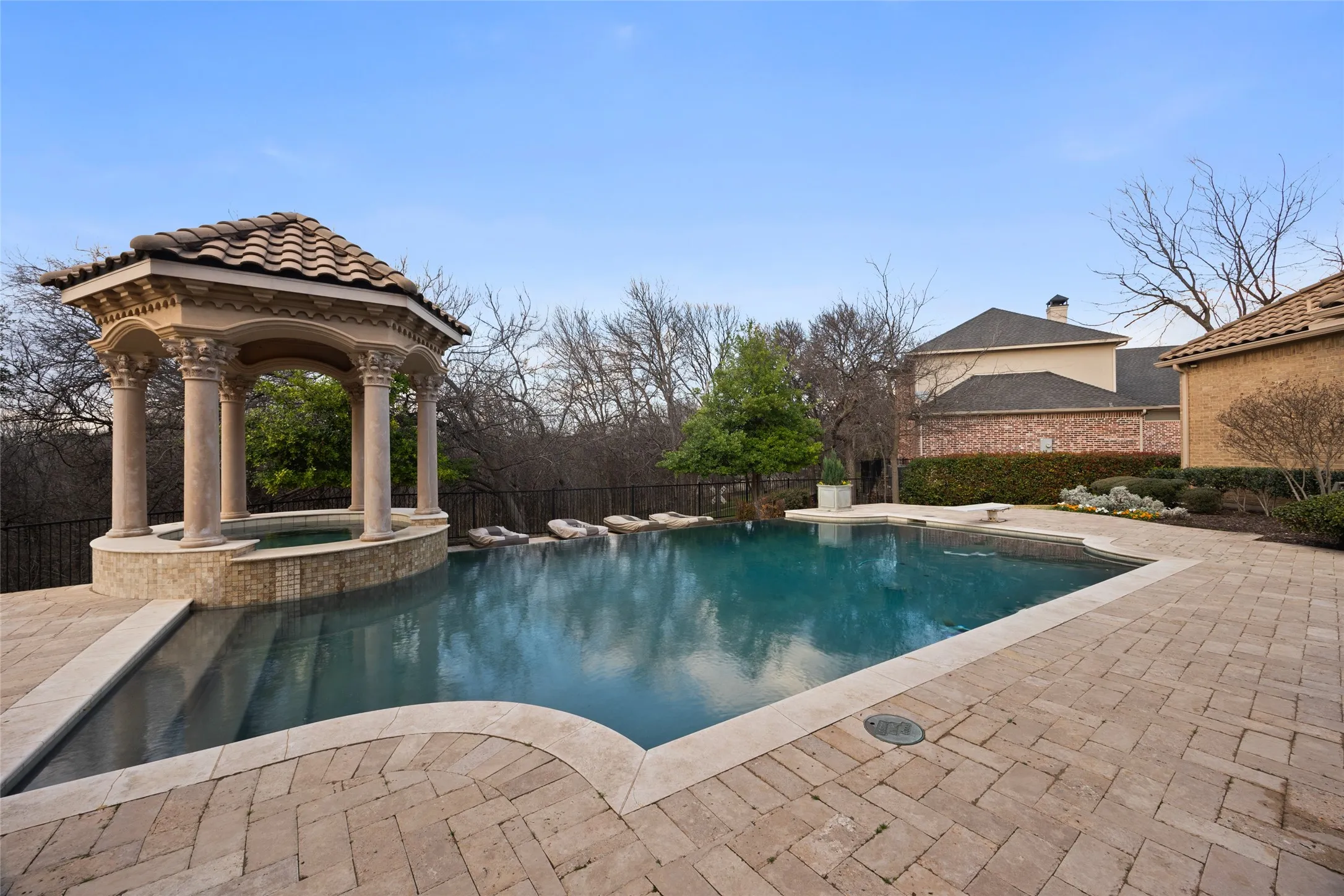 Expansive outdoor space featuring a swimming pool, integrated spa, and a tiled gazebo