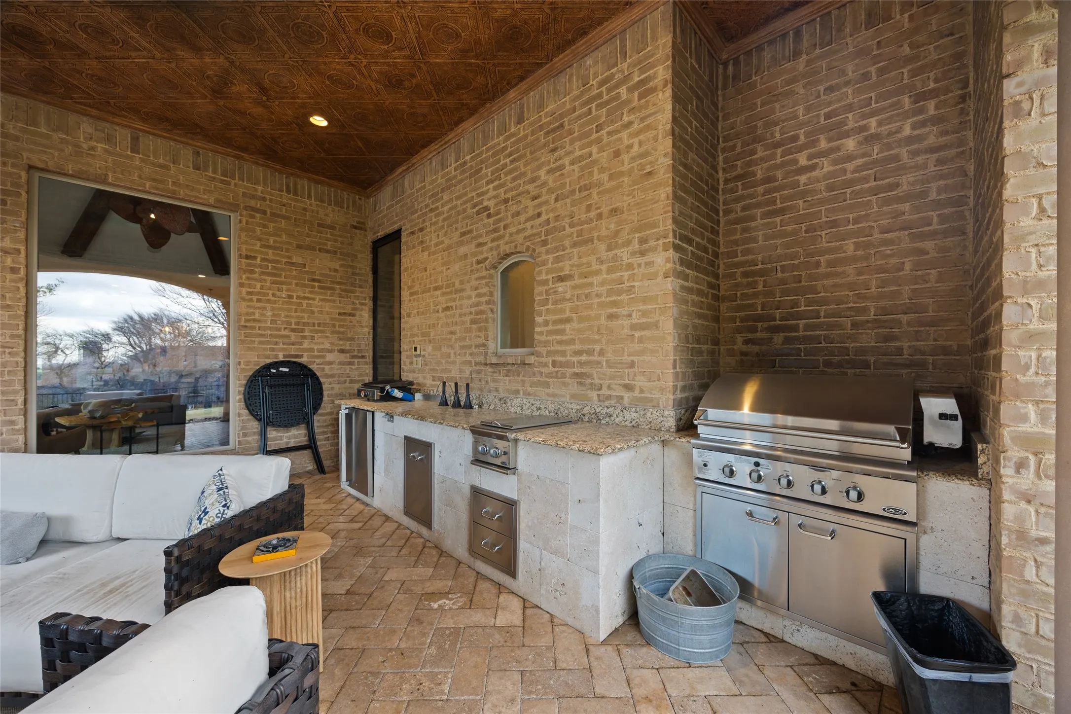 Outdoor kitchen featuring a built-in stainless steel grill, integrated sink, and stone countertops