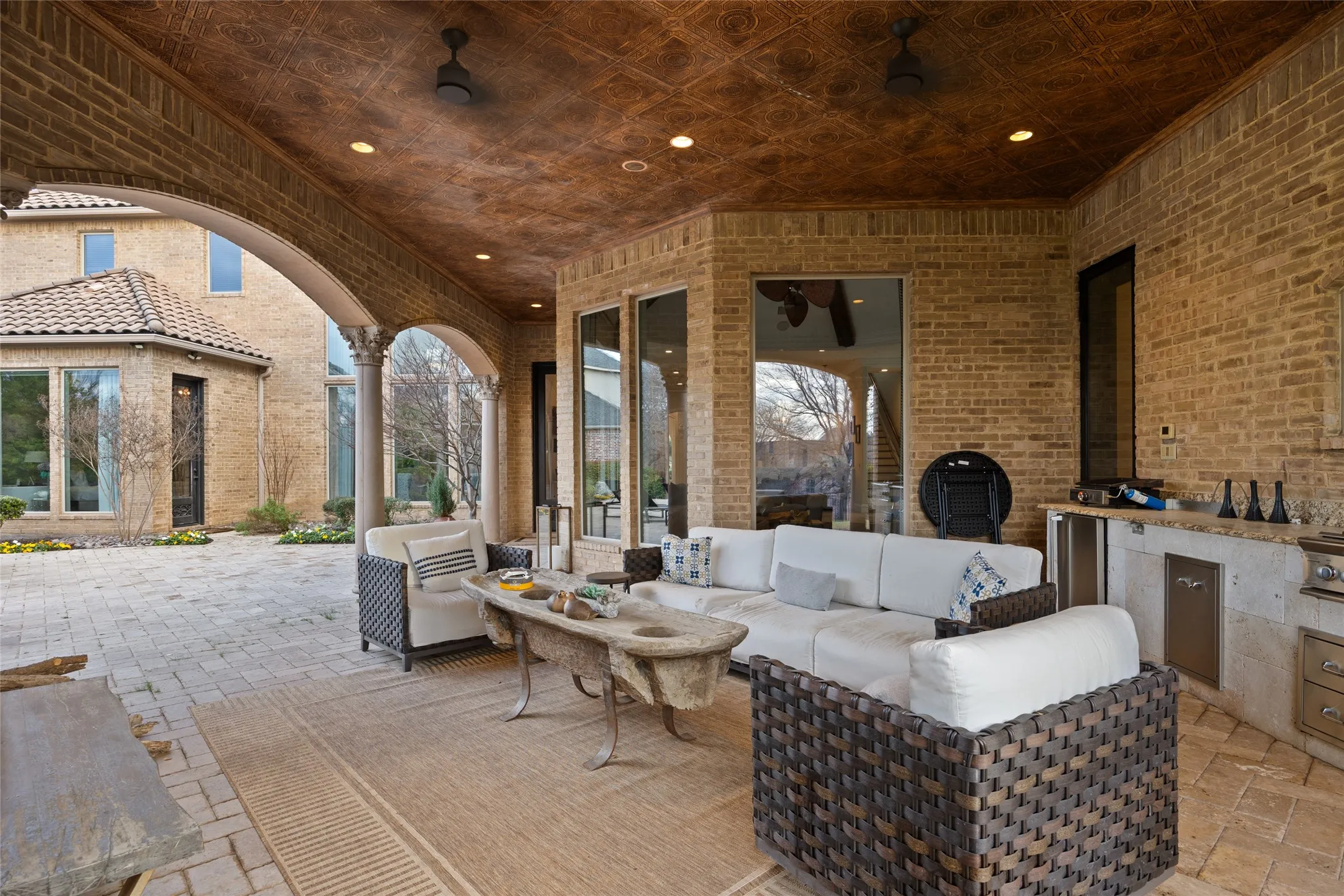 Expansive covered patio featuring a textured ceiling, recessed lighting, and a built-in outdoor kitchen with integrated appliances