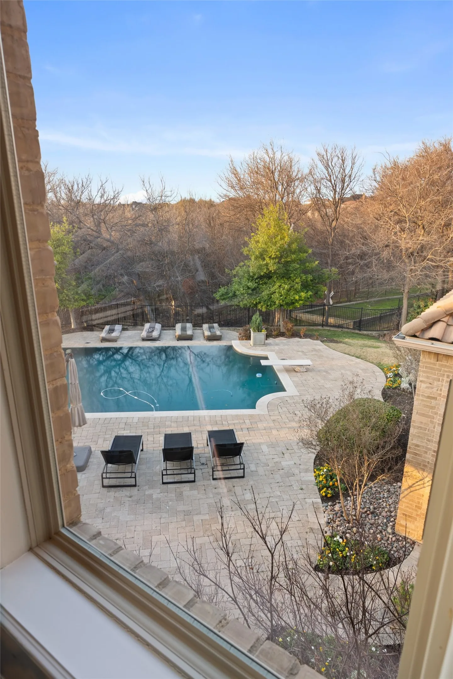 Outdoor swimming pool with integrated diving board, surrounded by stone paver patio