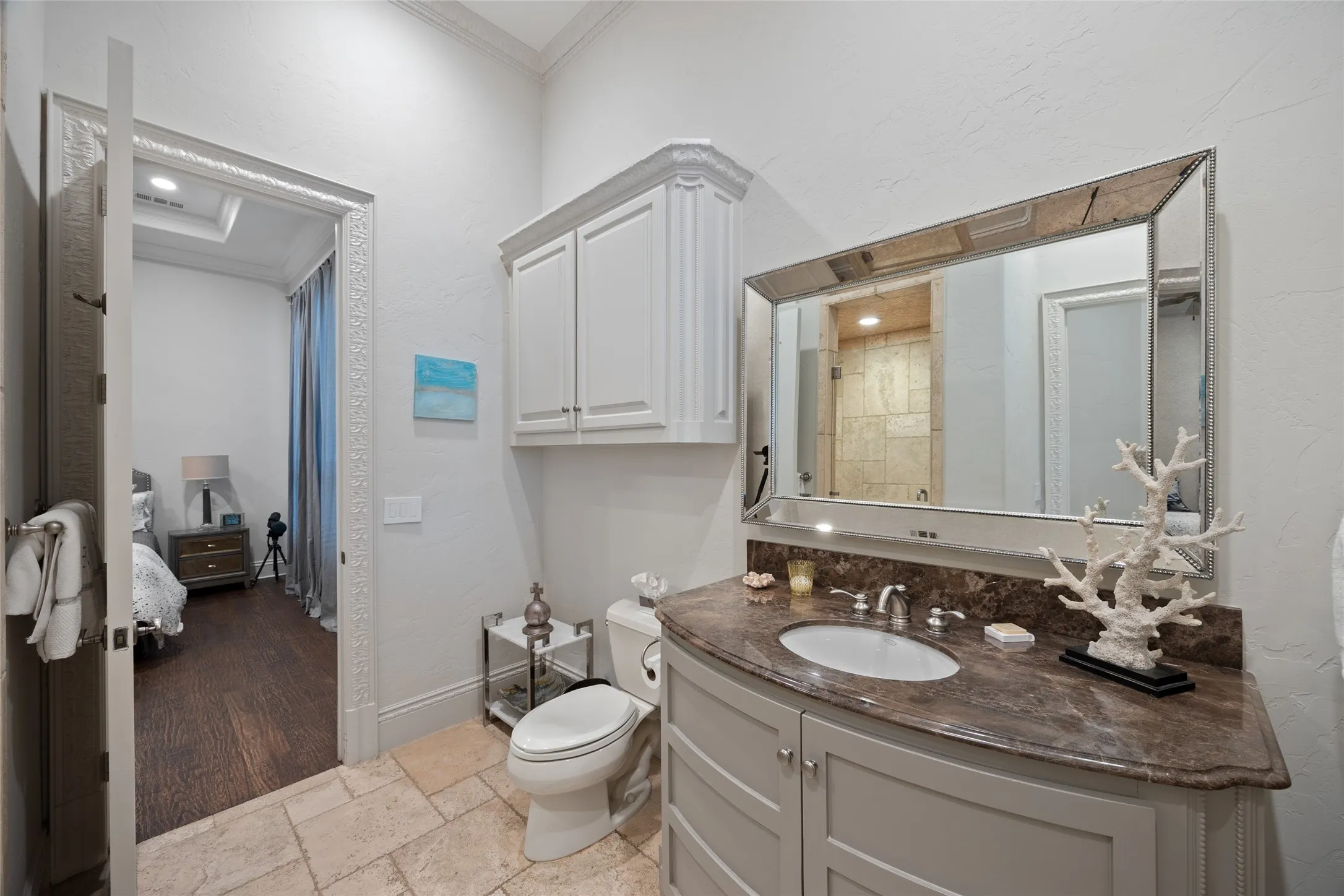 Curved vanity with an undermount sink, stone countertop, and custom cabinetry