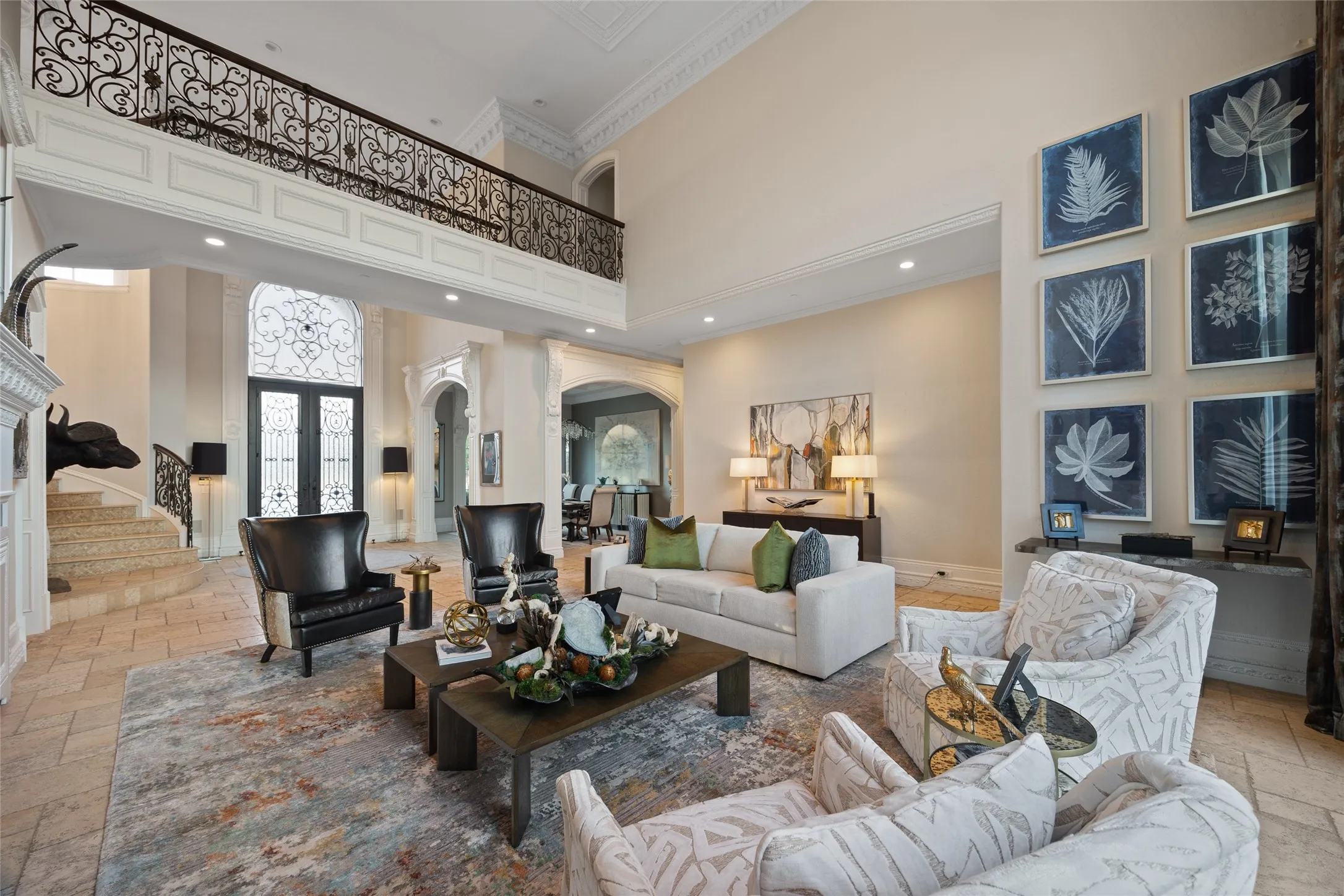 Two-story living area with high ceilings, wrought iron balcony railing, and ornate double entry doors
