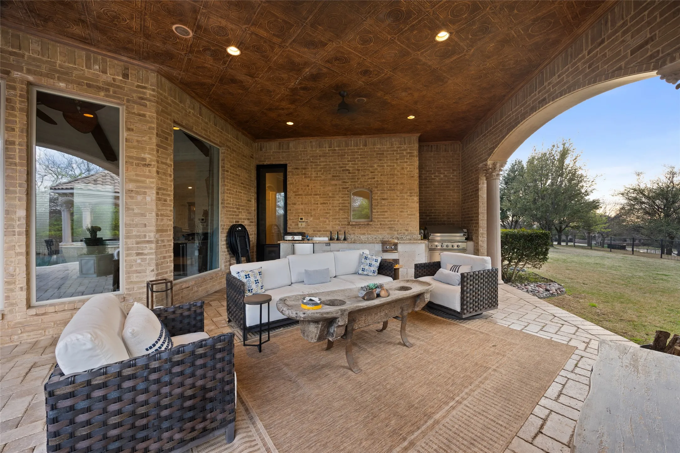 Covered patio featuring a patterned ceiling, brick walls, and an arched walkway