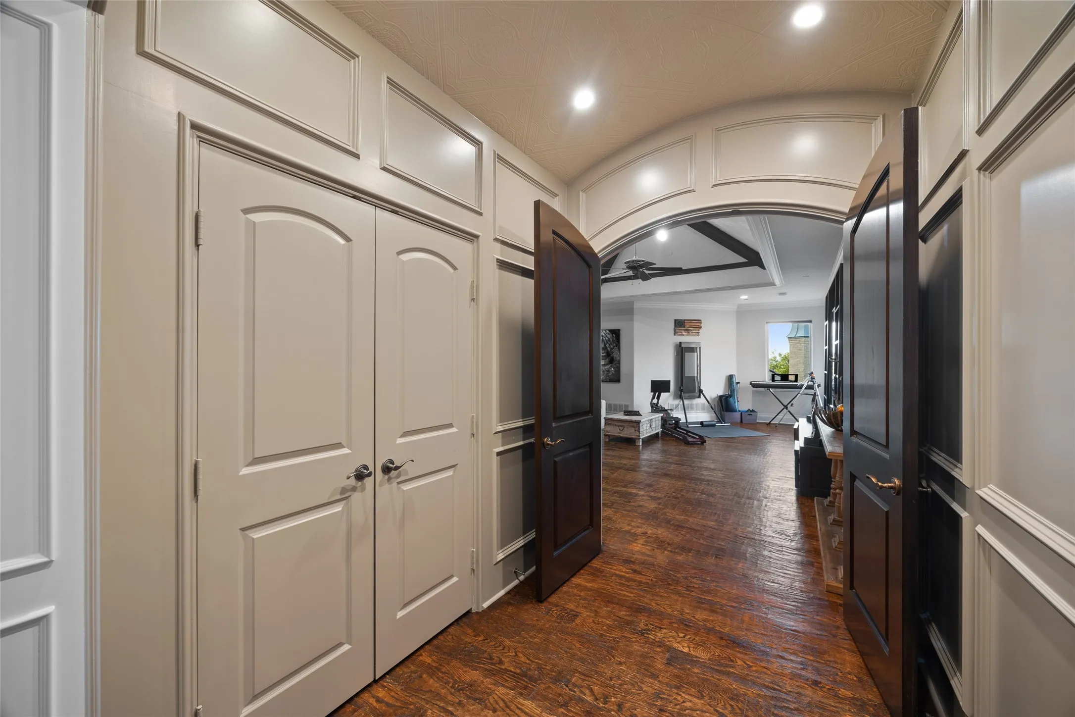 Arched entry with recessed lighting, wood-finish flooring, and wainscoting details