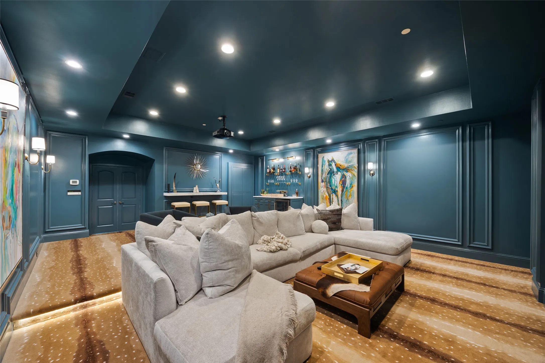 Recessed lighting illuminates the deep teal walls with decorative panel molding